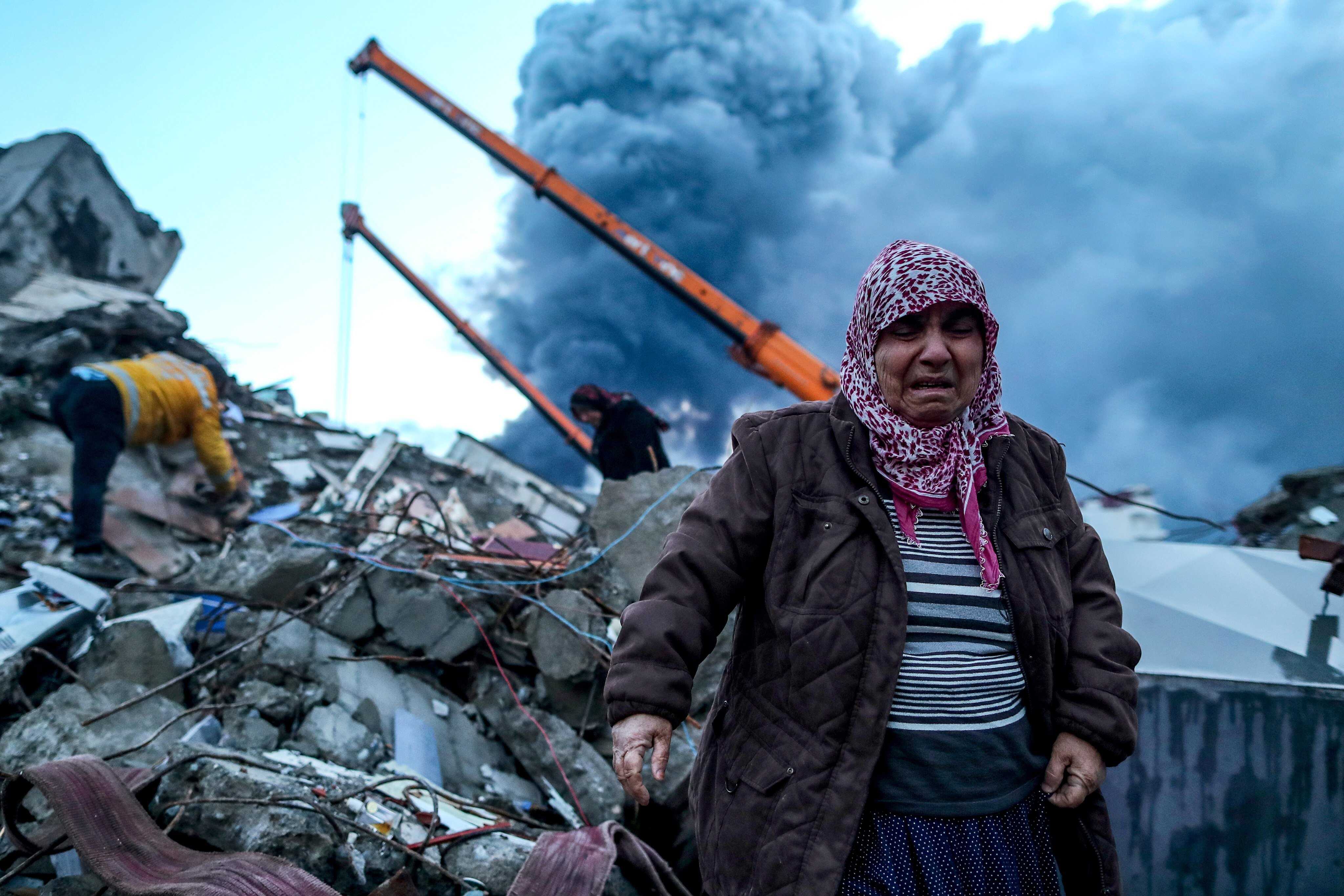 A woman stands near the site of a collapsed building as emergency personnel search for victims after the earthquake in Turkey. Photo: EPA-EFE