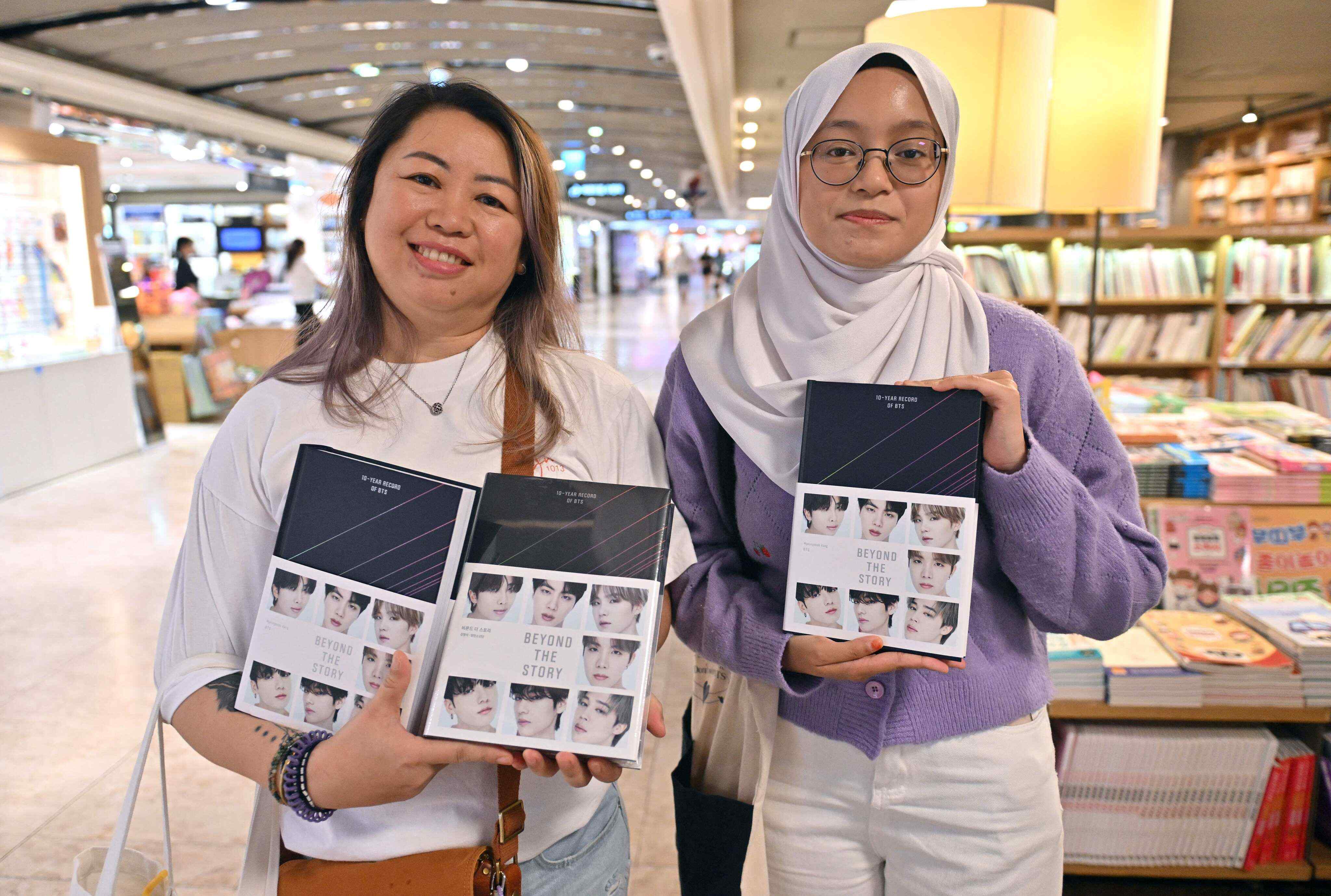 Malaysian BTS fans Aiudrey (L) and Aqilah (R) hold copies of the BTS memoir “Beyond the Story: 10-Year Record of BTS” at a bookstore in Seoul on July 9, 2023. Photo: AFP