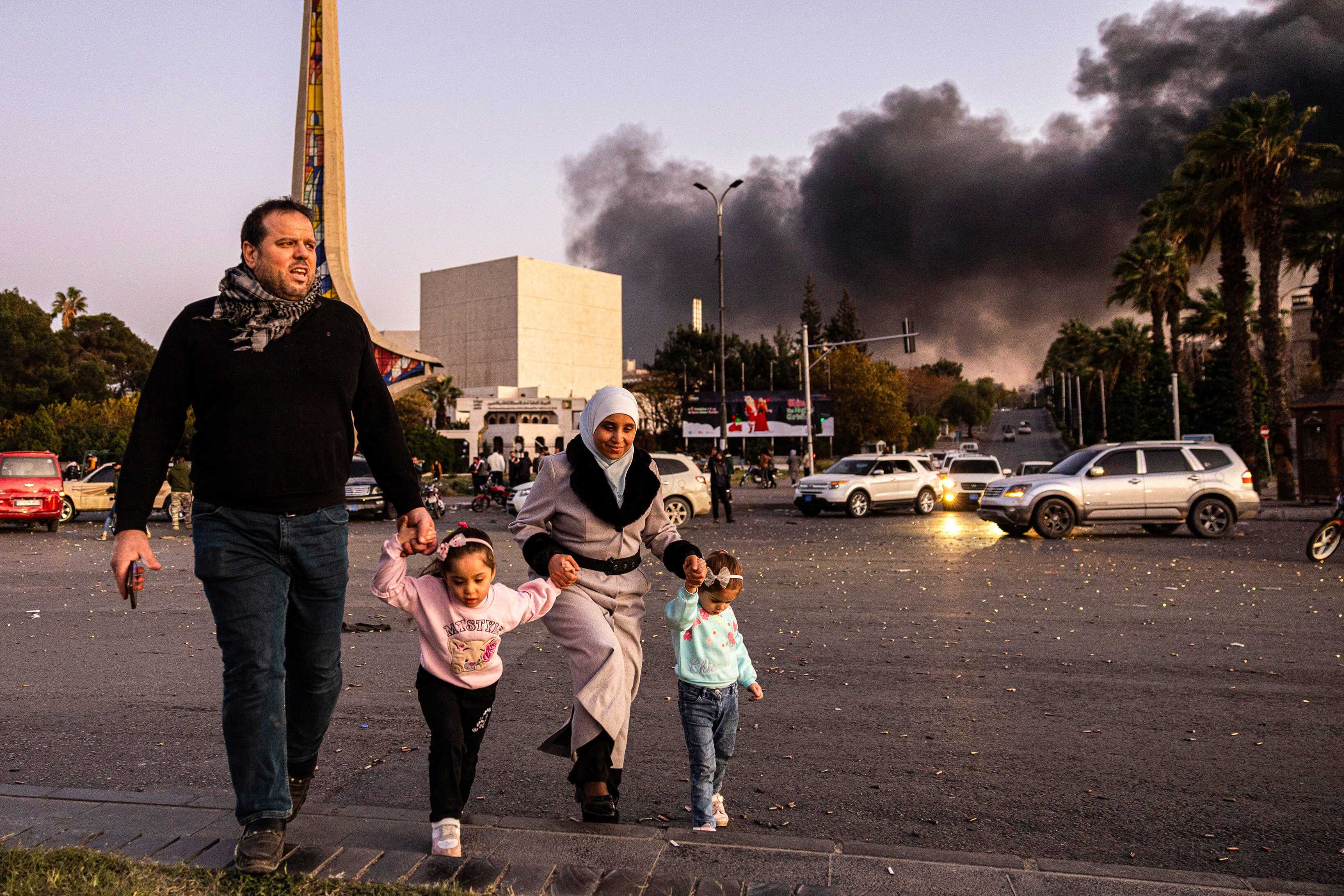 Smoke billows as people arrive to celebrate the fall of the Syrian government in Damascus on December 8, 2024. Photo: Ugur Yildirim/Dia Photo via AP