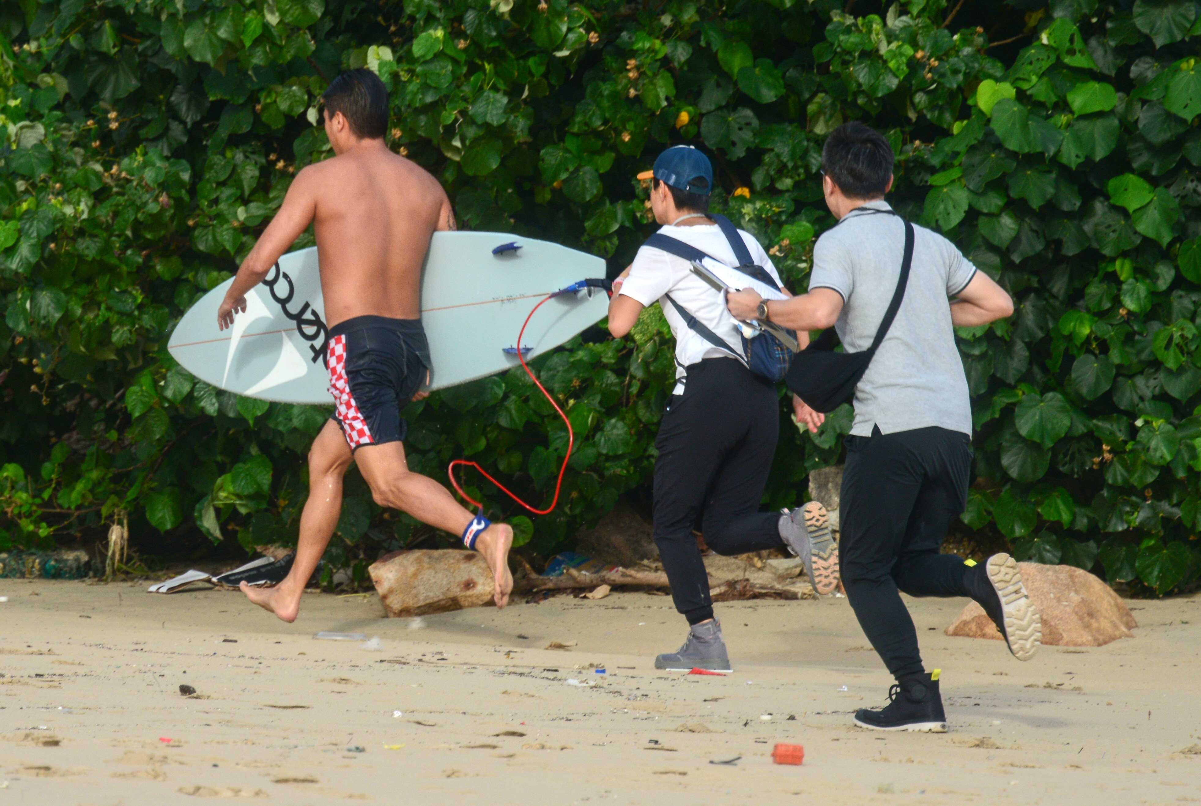 A surfer runs away from Leisure and Cultural Services Department staff trying to get his details. Photo: Antony Dickson