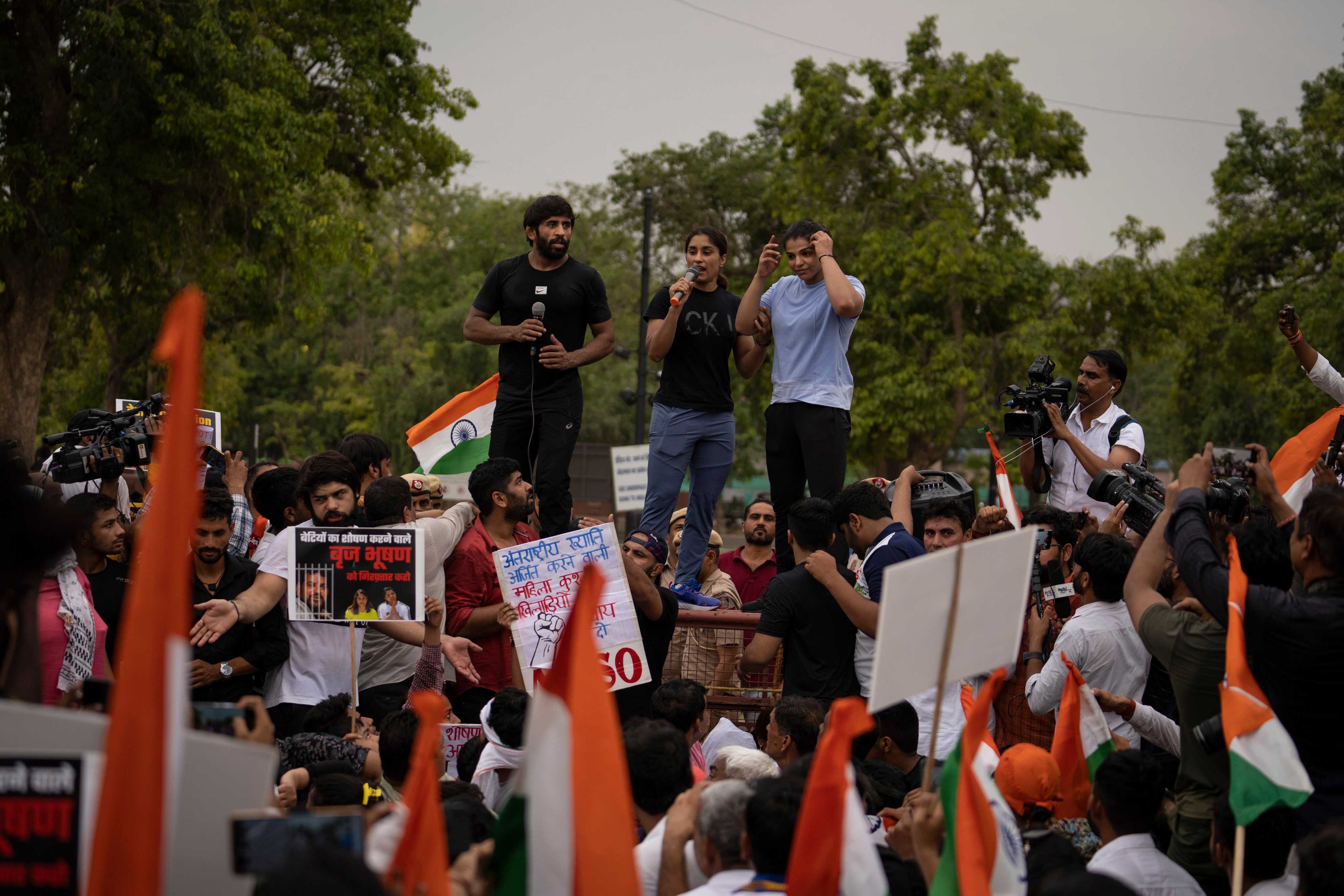 (From left) Indian wrestlers Bajrang Punia, Vinesh Phogat and Sakshi Malik stand on a police barricade during a march against Brij Bhushan Sharan Singh, the president of the Wrestling Federation of India, during a protest against sexual harassment in their industry in 2023. Photo: AP 