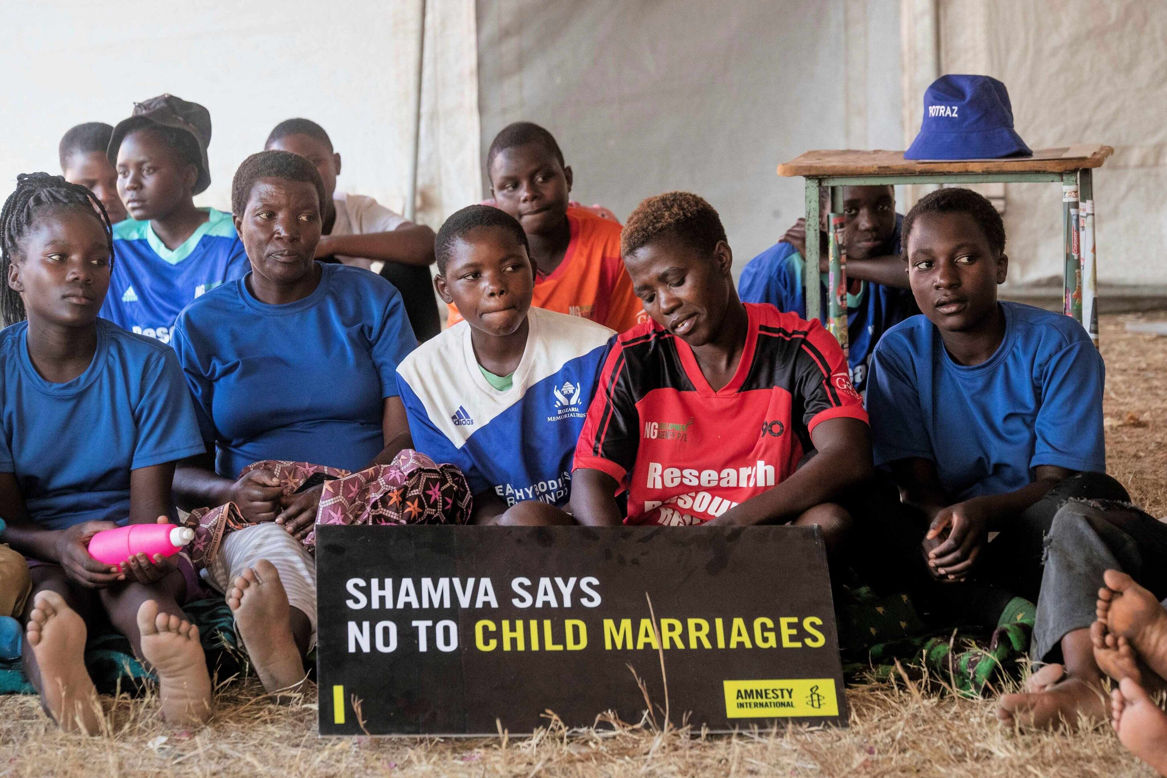 Girls and women sit inside a tent as they listen to their mentor speaking to them about child marriages in Zimbabwe. Photo: AP