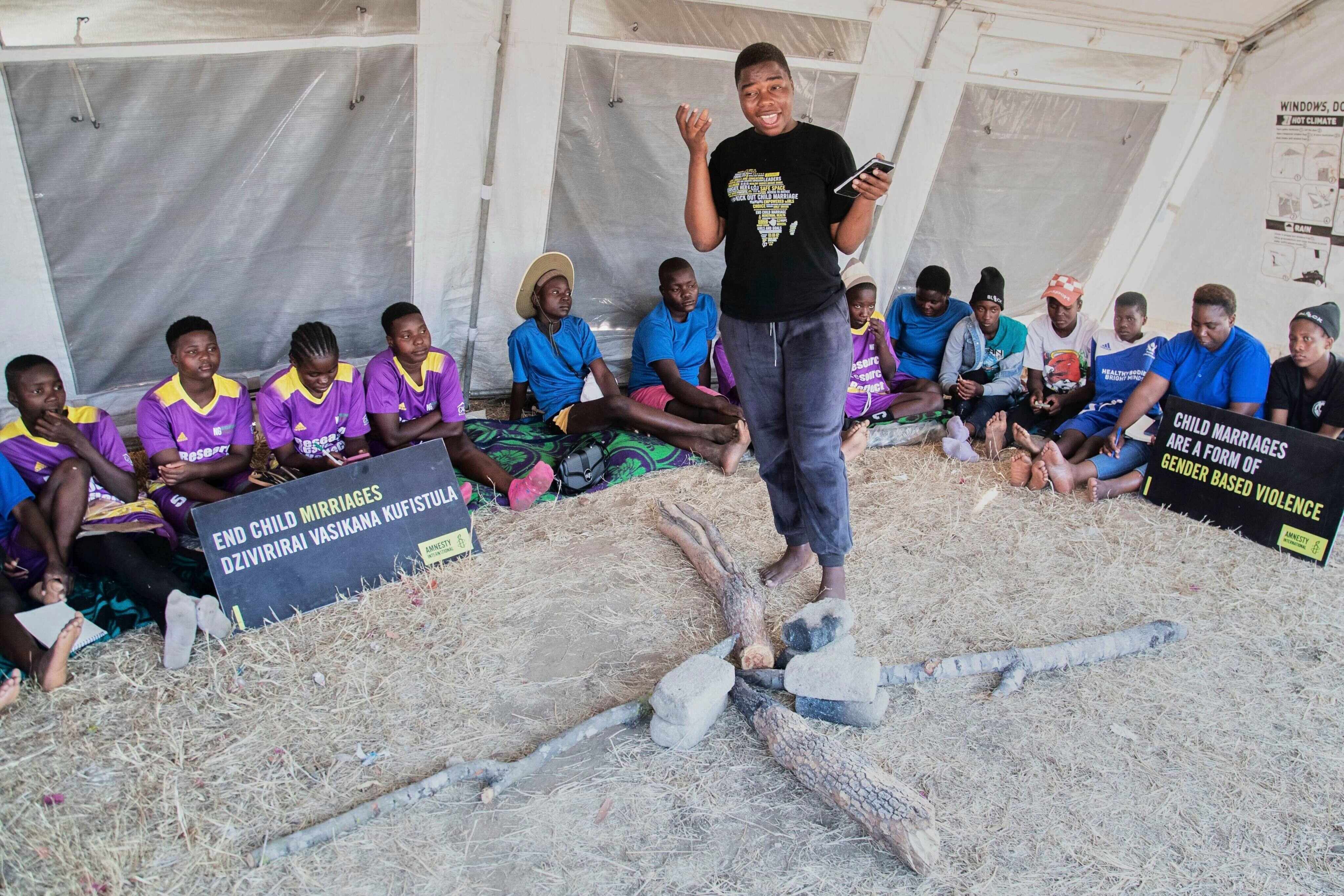 Women and girls sit in a tent as their mentor speaks about child marriages in Zimbabwe. Photo: AP