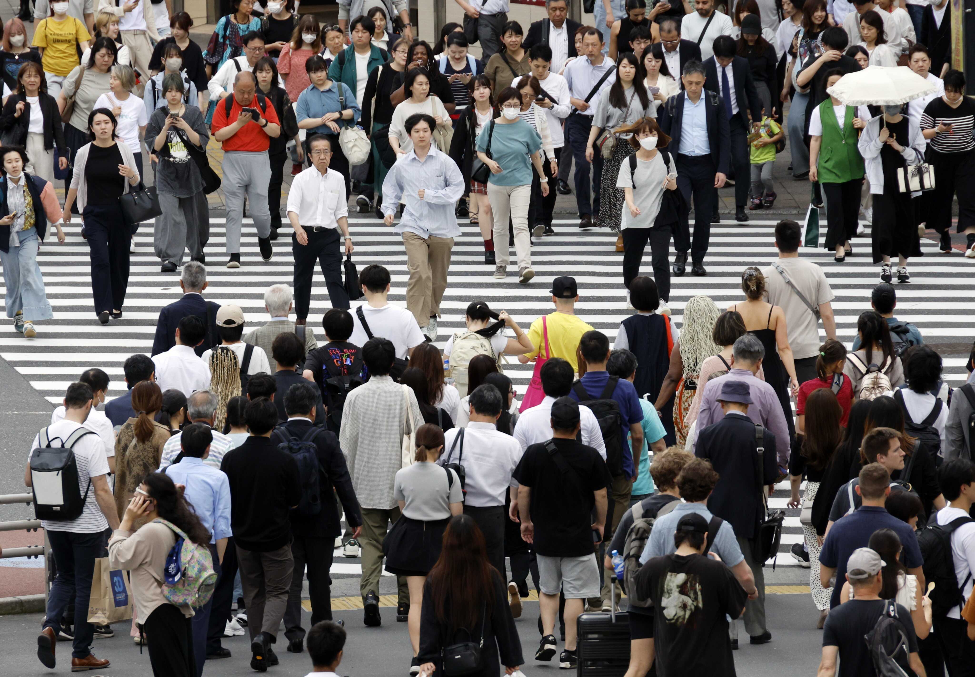 Pedestrians cross a road in Shinjuku, Tokyo. The rising popularity of corporate-only dating apps in Japan comes amid a decline in its birth rate. Photo: EPA
