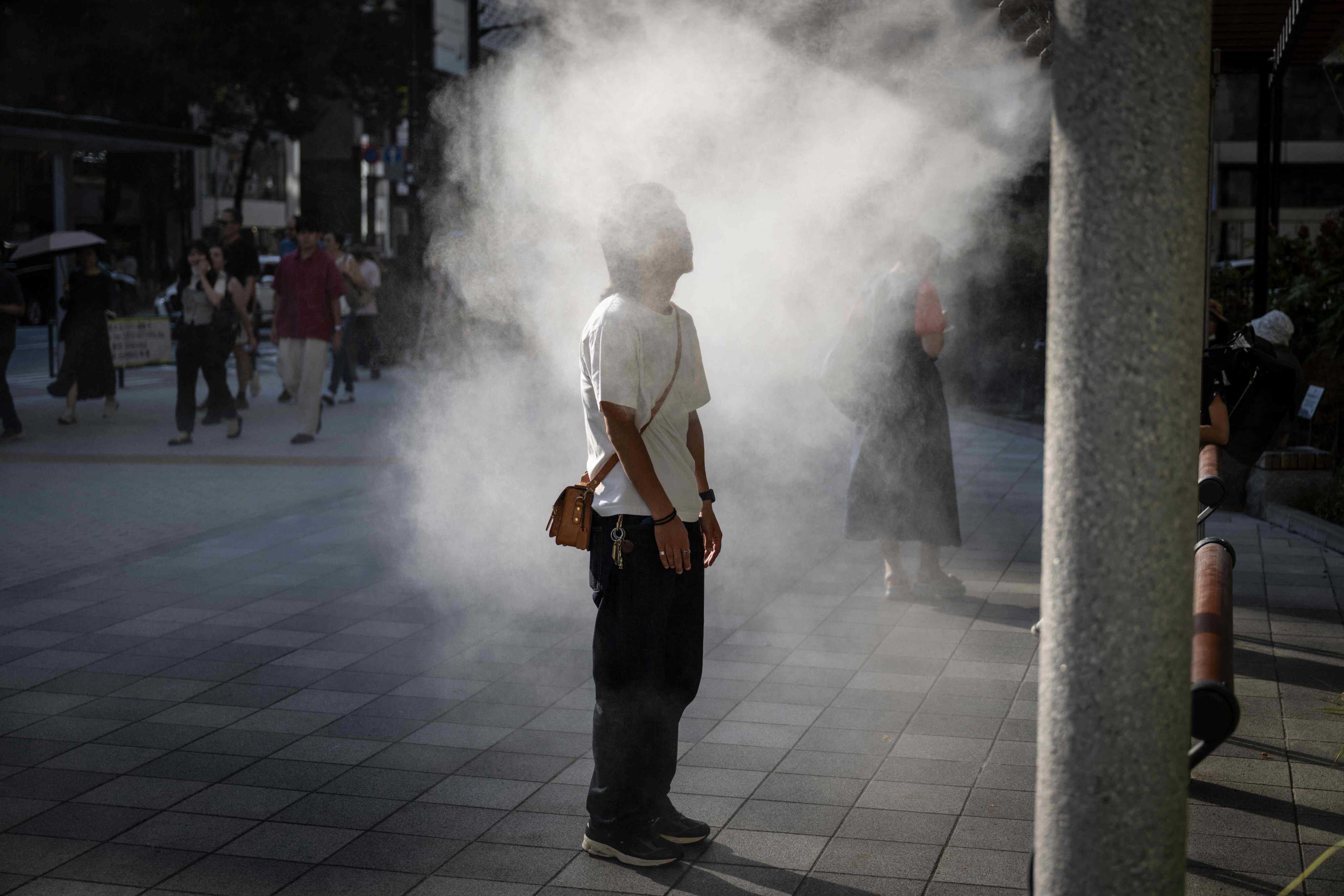 A man rests under a water misting system to cool down on a hot day in Tokyo, Japan. Photo: AFP