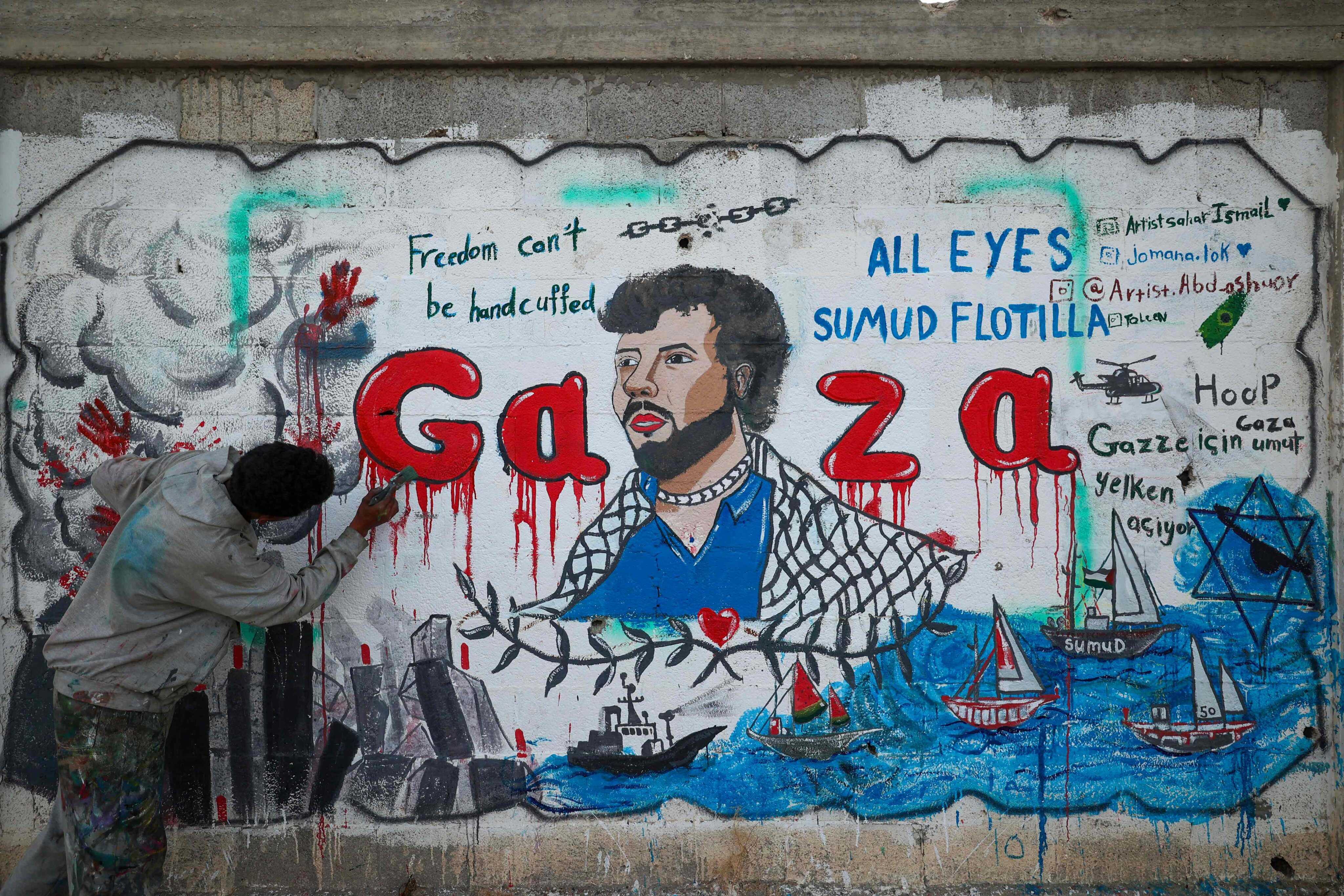 A Palestinian artist paints a mural depicting Israel’s interception of ships participating in the Global Sumud Flotilla, a civilian-led humanitarian aid mission to Gaza by sea, in Nuseirat in the central Gaza Strip on May 19. Photo: AFP