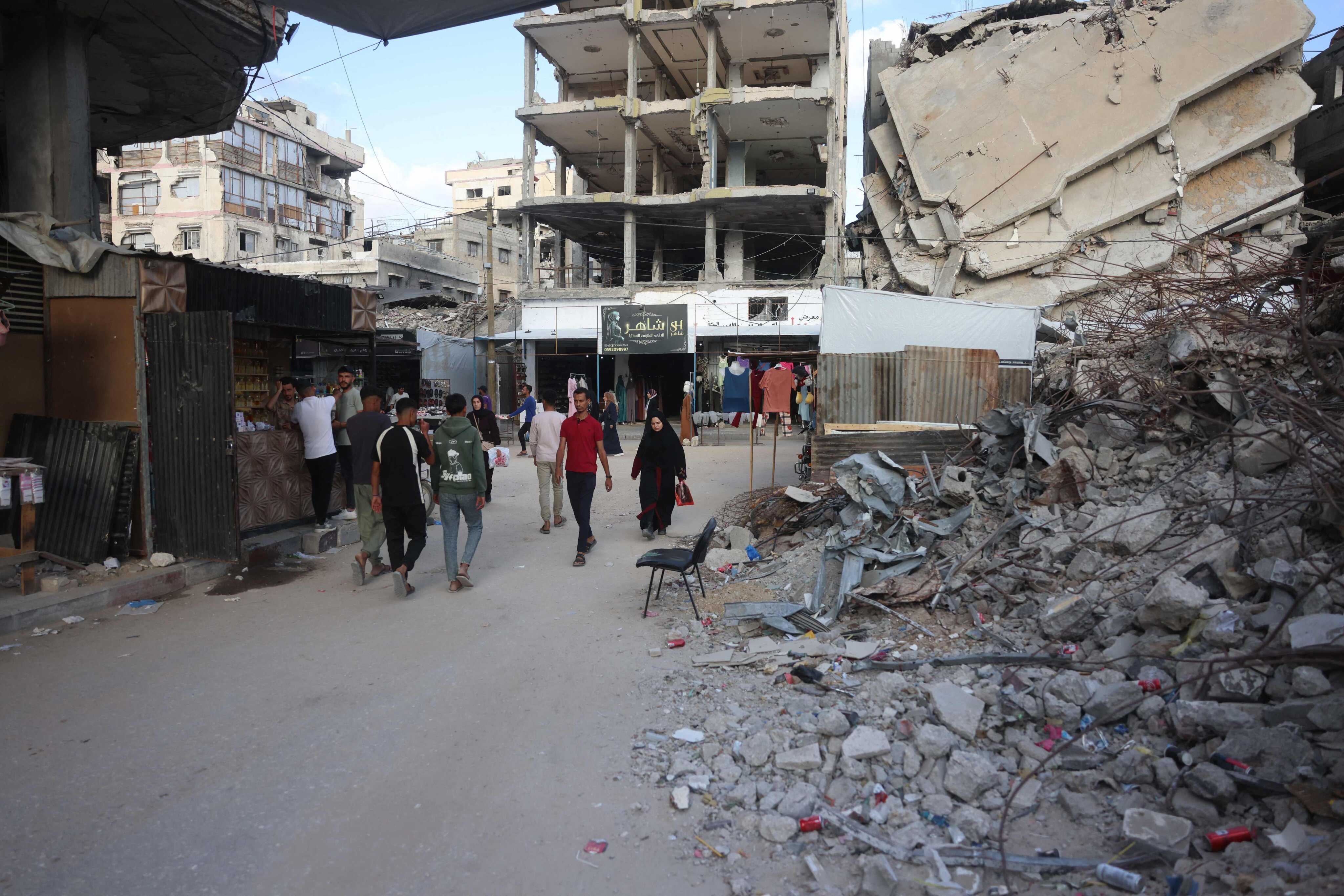 Palestinians make their way past the rubble of buildings destroyed in Israeli military strikes, as they shop on the eve of the Muslim holiday of Eid al-Adha. Photo: AFP