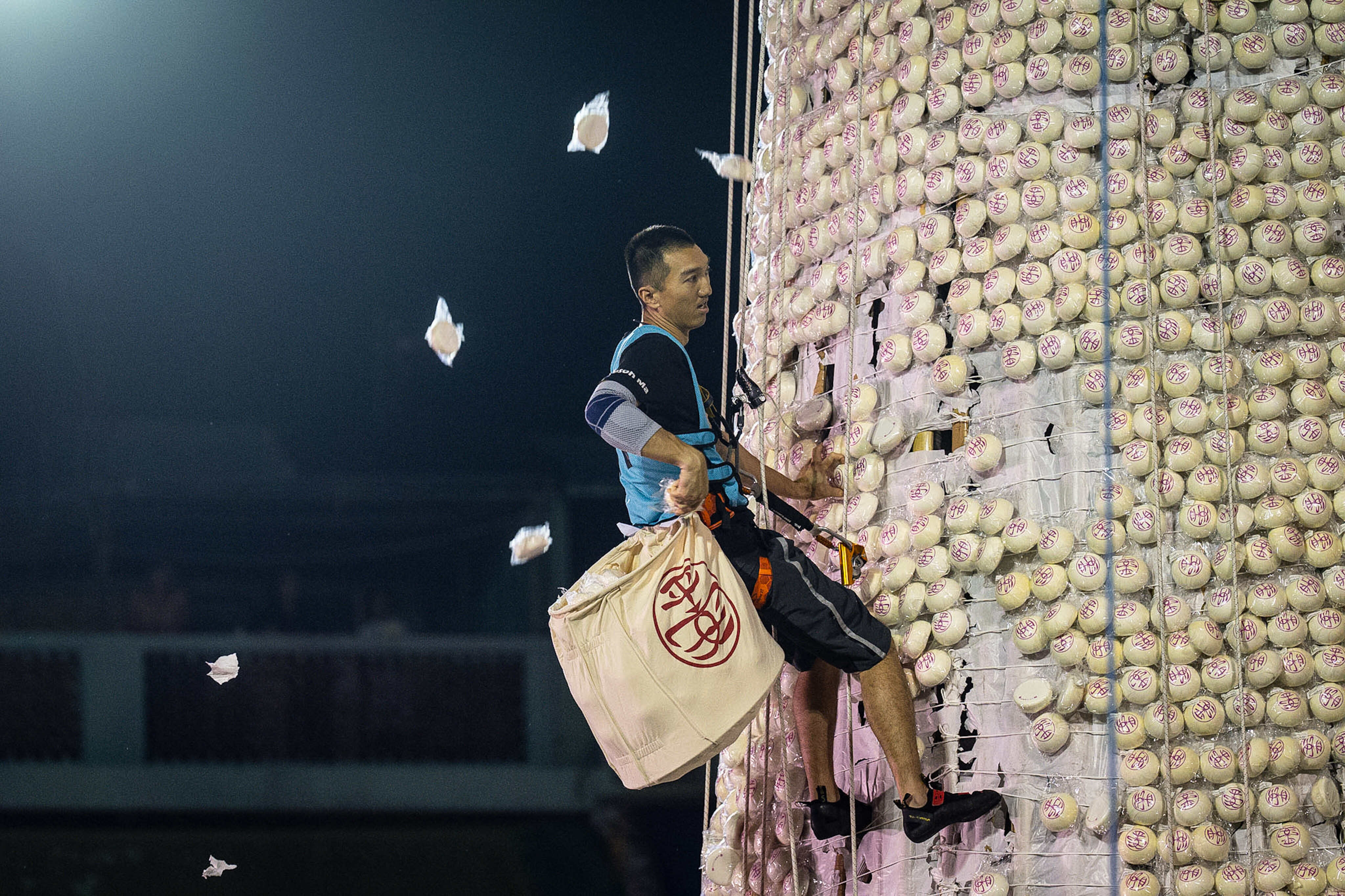 A participant collects buns from a tower covered with plastic buns during the Bun Festival in Cheung Chau Island in Hong Kong on May 25, 2026. Photo: AP