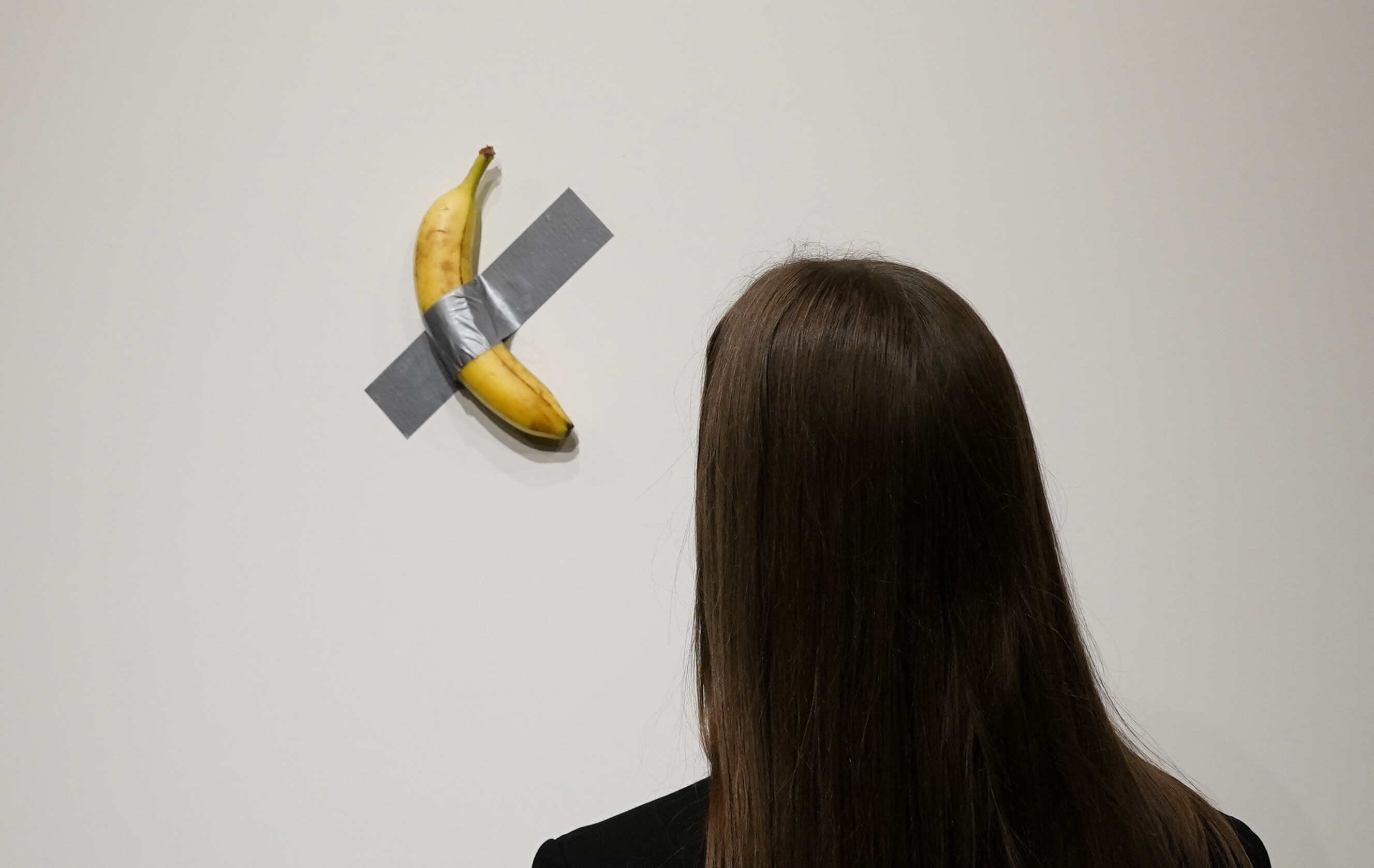 A person looks at Italian visual artist Maurizio Cattelan’s duct-taped banana entitled “Comedian,” during a press preview at Sotheby’s in New York, on October 25, 2024. Photo: AFP