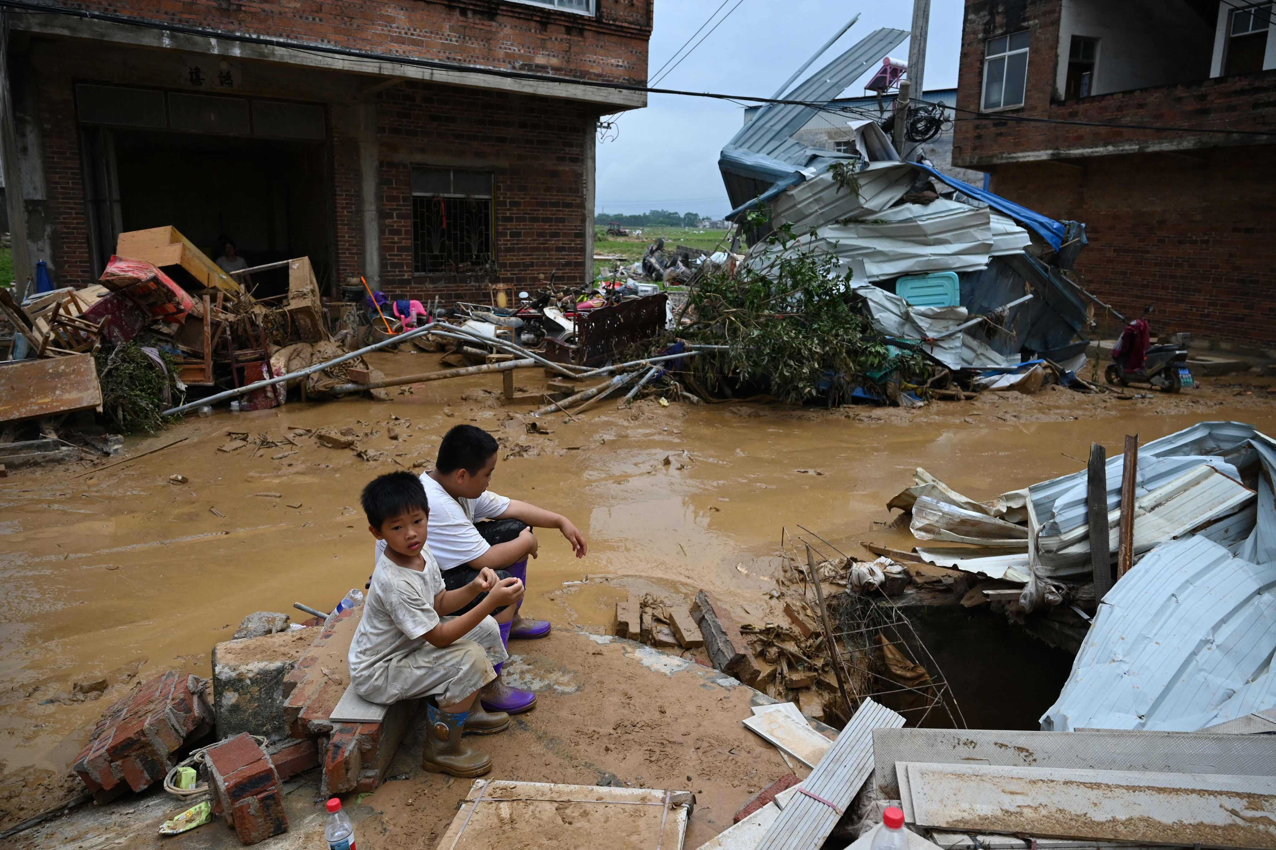 Children sit next to houses in Liulan village, in Hengzhou city, in Chinas southwest Guangxi region on July 8. The houses were damaged when the Liulan reservoir collapsed on July 6. Photo: AFP