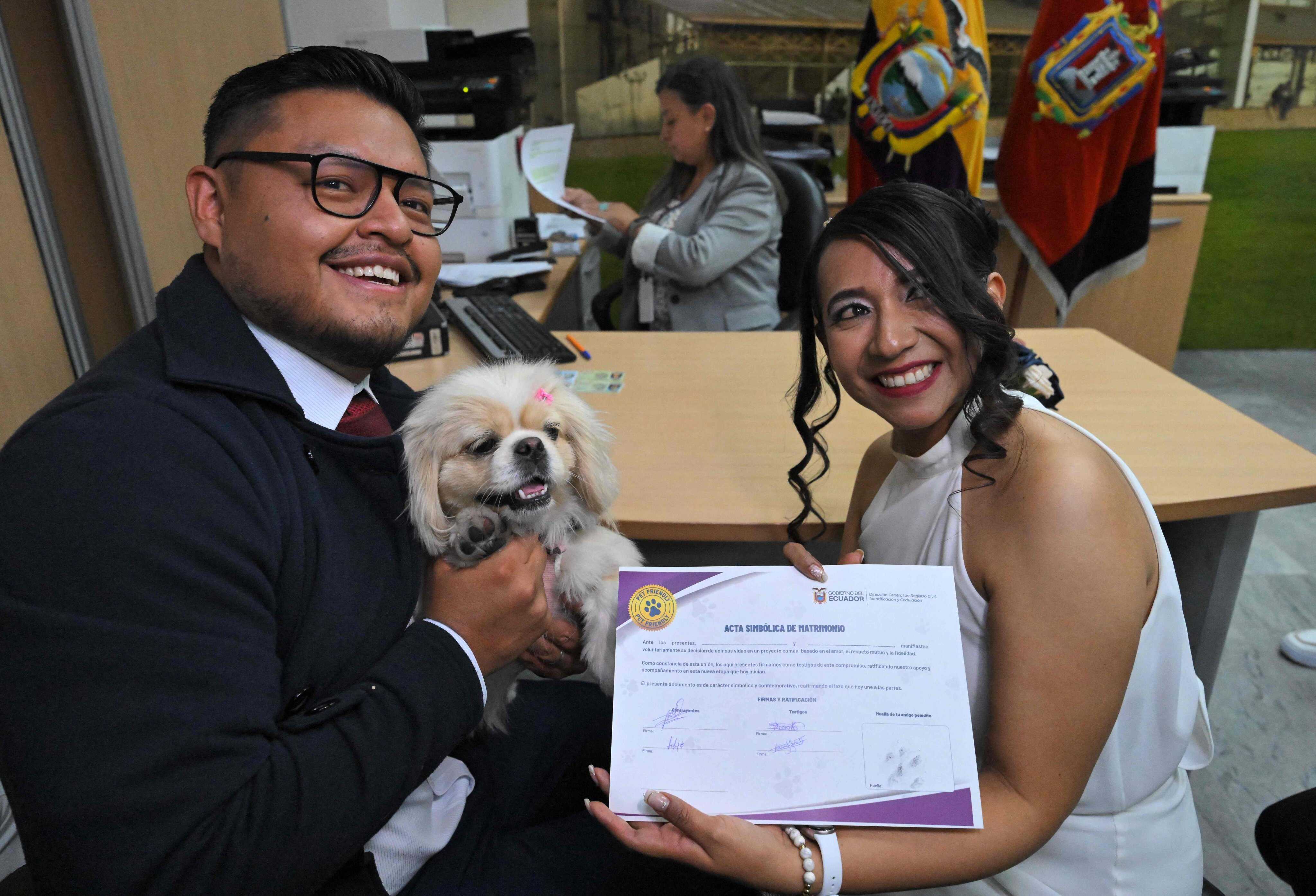 Andres Alquiga and Diana Tupiza pose with their dog Luna, showing off the symbolic marriage certificate with their pet's "signature" after their wedding at the central civil registry office in Quito, Ecuador on July 7, 2026. Photo: AFP