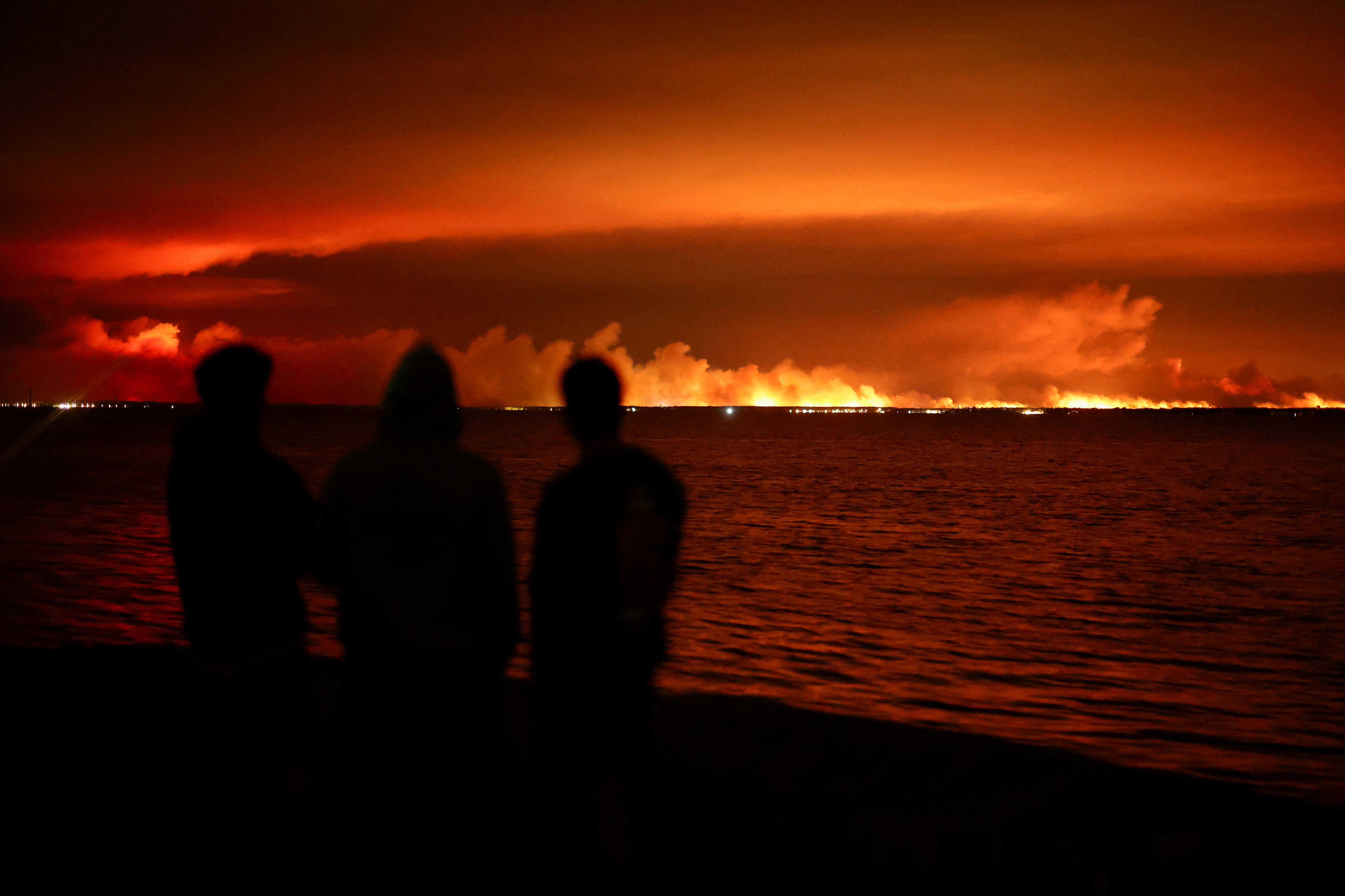 Tourists watch a wildfire burn in a forest area near Arcachon Bay from Gujan-Mestras, in the Gironde area of France, amid worsening drought conditions following a heatwave and water shortages across much of the country. Photo: Reuters