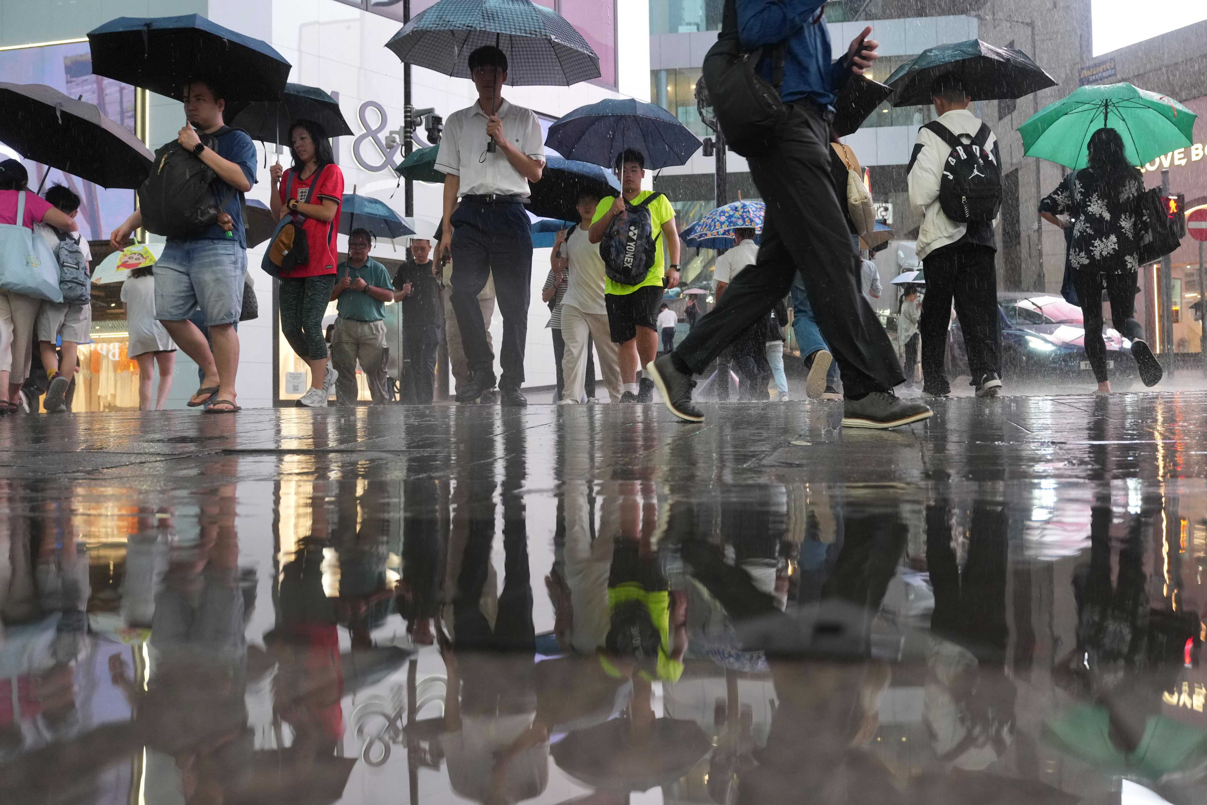 Pedestrians hold umbrellas as they make their way across the street in Central during a heavy downpour in Hong Kong. Photo: Karma Lo