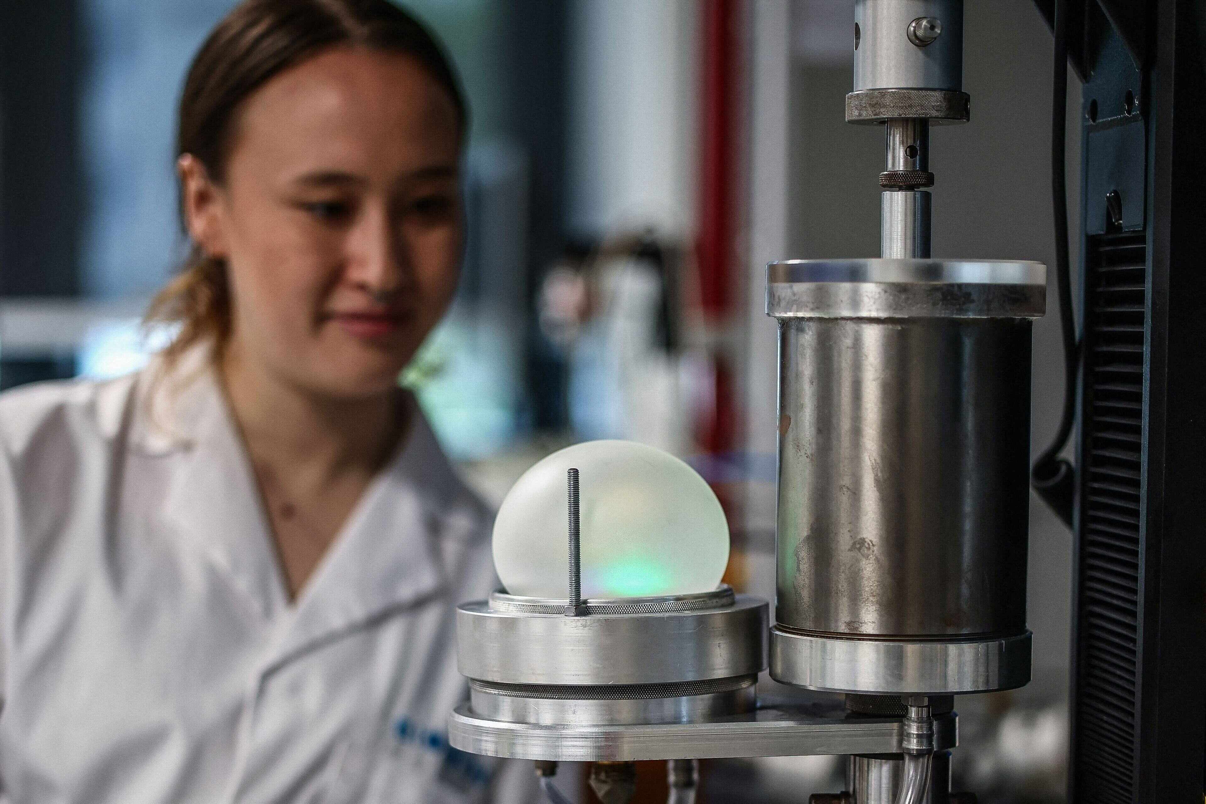 Co-inventor of Bioloon, Juliana Cumming, shows how a piece of fully biodegradable rubber can be inflated into a balloon. Photo: AFP