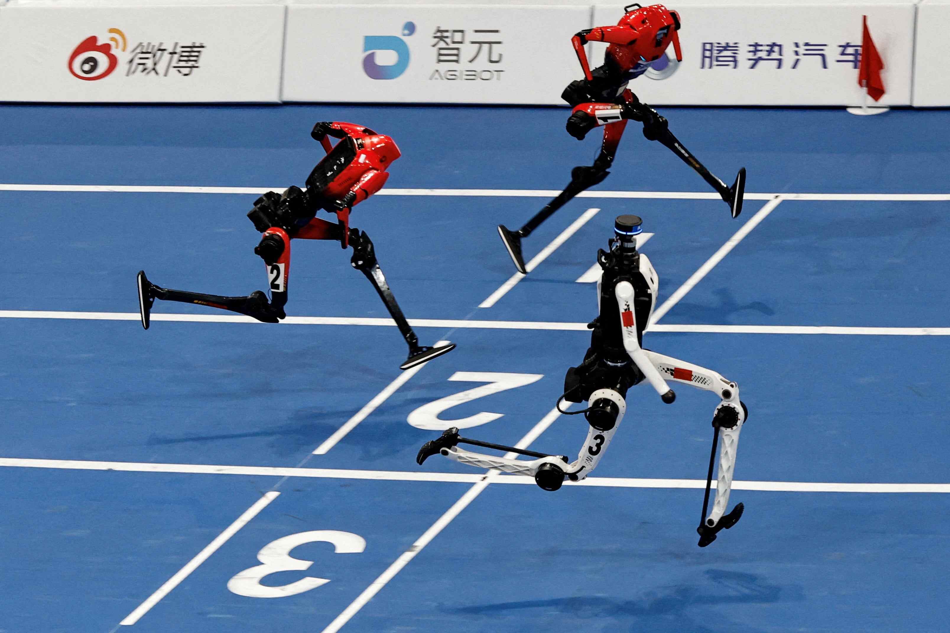 A Tiangong Ultra humanoid robot crosses the finish line in 8.86 seconds, next to Honor humanoid robots, during a 100-metre large-size group semifinal race at the 2026 World Humanoid Robot Games. Photo: Reuters