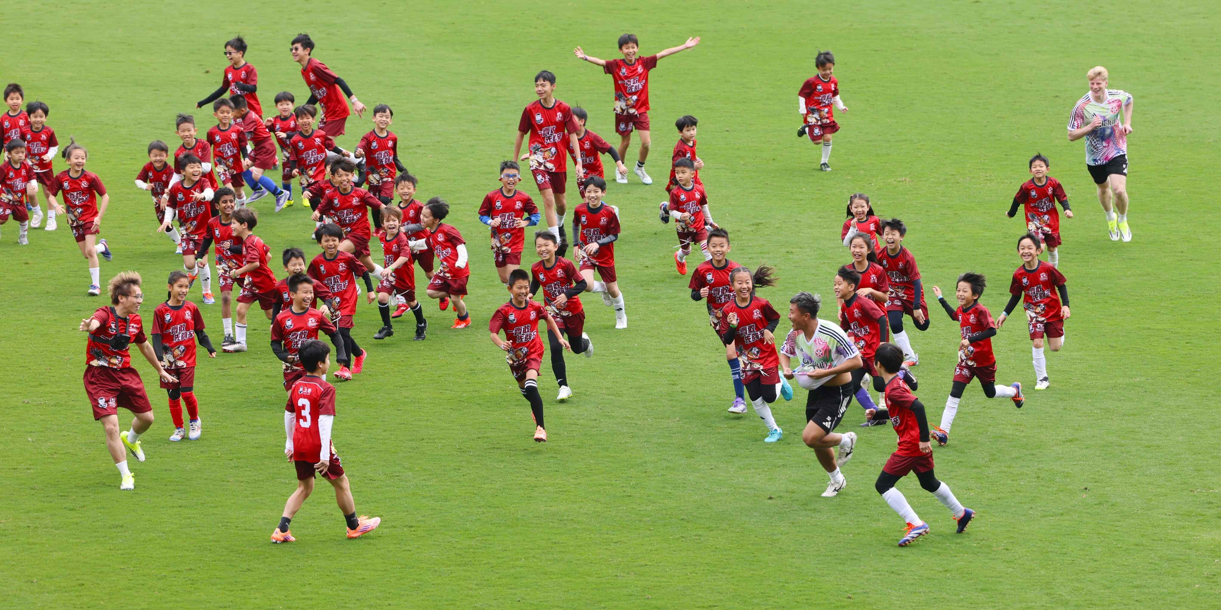 One hundred young footballers aged six to 12 battle against three players from the Hong Kong Premier League’s Eastern Football Club at Kai Tak Youth Sports Ground. Photo: Nora Tam