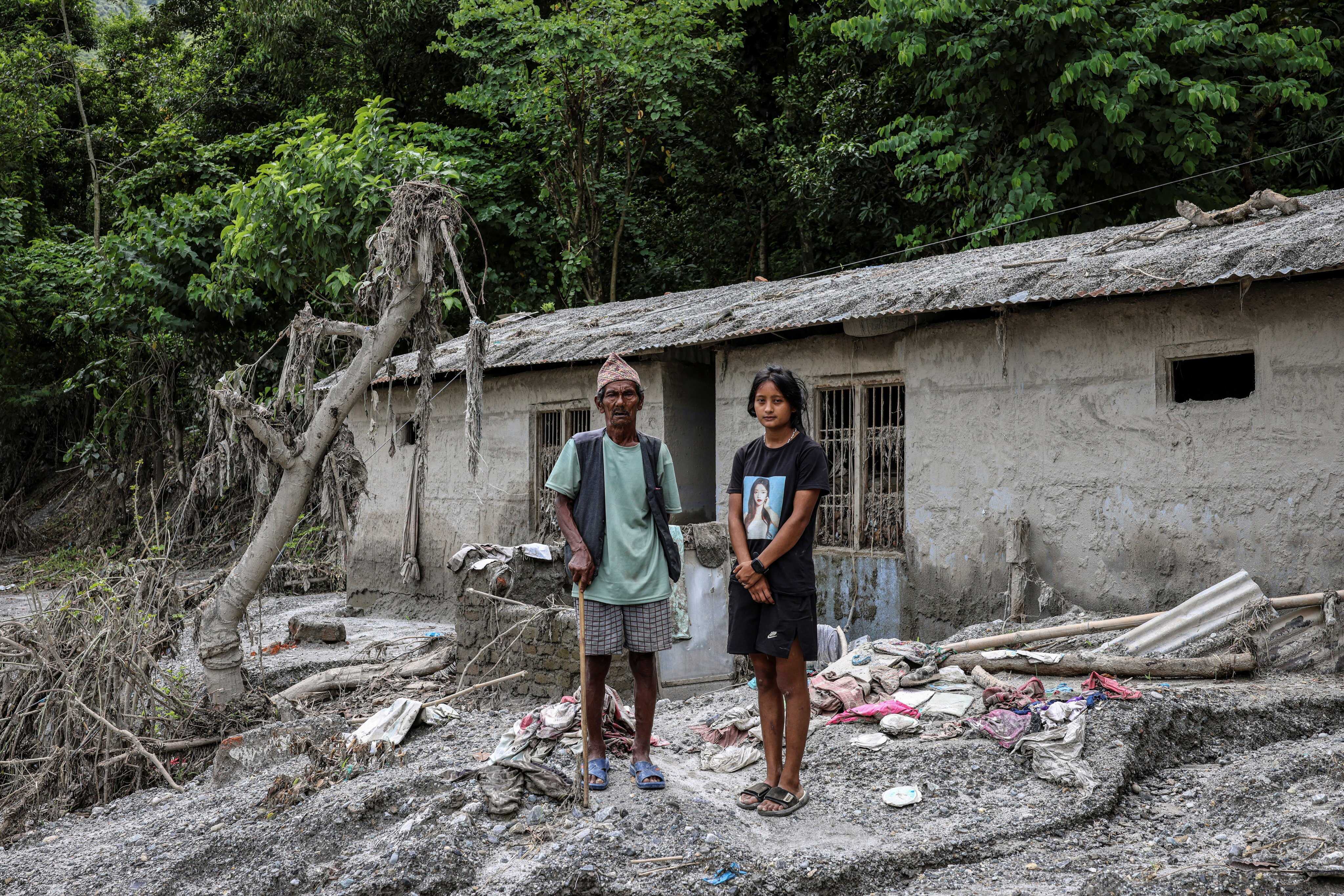 Sachita Rai, 19, and her grandfather Man Bahadur Rai, 80, stand outside their home after thick mud flooded the interior of the structure in Ratamate, Nuwakot district, Nepal. Sachita said she was helping her grandfather on a vegetable farm when floodwaters arrived and rushed to bring him to safety. “I risked my life to save my 80-year-old grandfather,” she said. Photo: Reuters