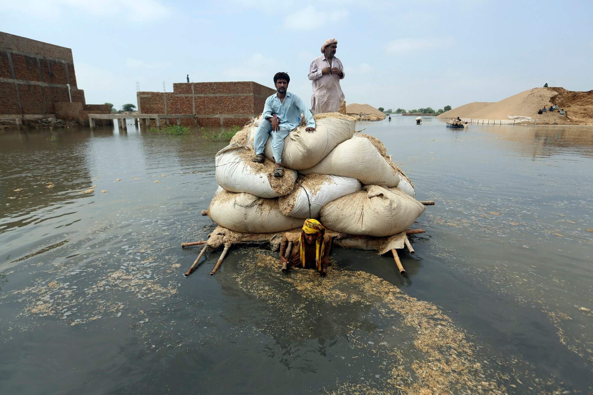 Flood victims use a makeshift barge to carry hay for cattle in Jaffarabad, a district of Pakistan’s southwestern Baluchistan province, on September 5, 2022. Photo: AP