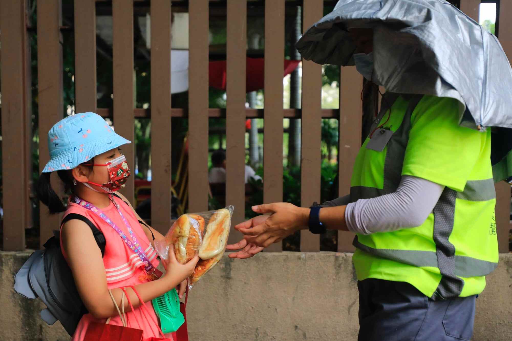 Six-year-old volunteer Boo Wu hands a bag of bread to a street cleaner in Yuen Long. Photo: Xiaomei Chen