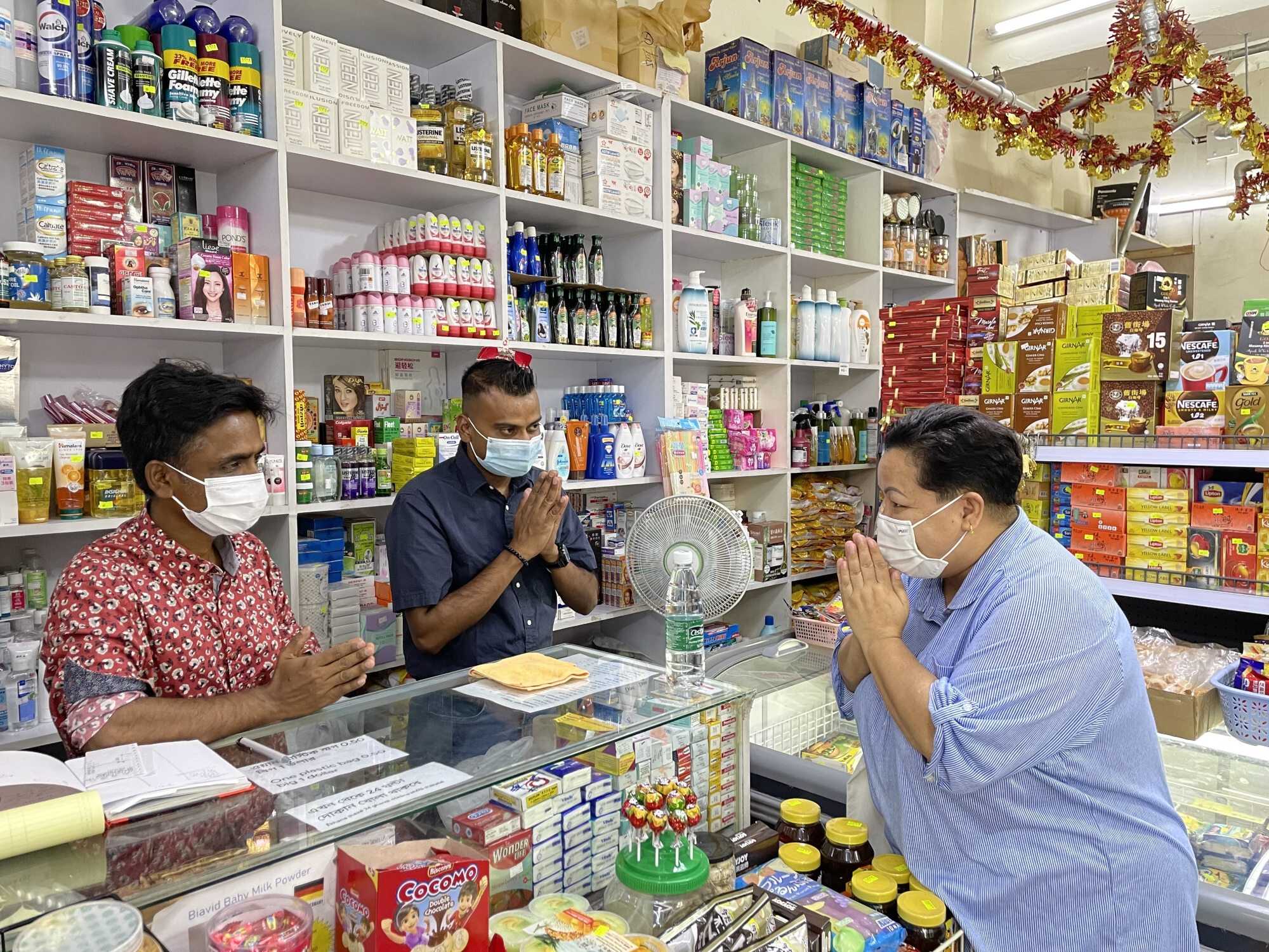 The owner of Jordan Mart in Man Wah Sun Chuen, Aftab Manik (left) greets community coordinator Judy Gurung (right) at his shop on Man Wai Street. Photo: Yanni Chow