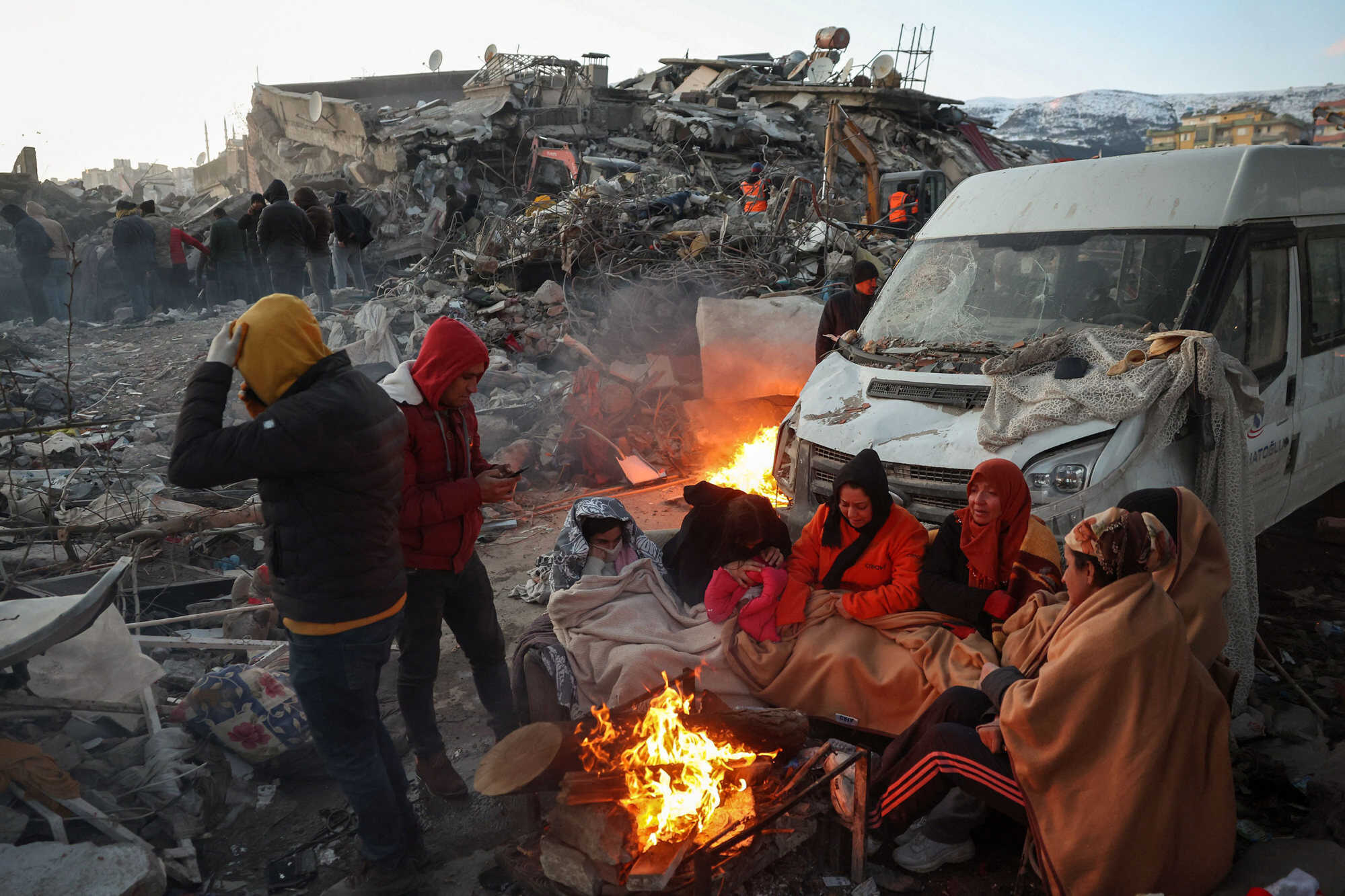 Survivors gather next to a bonfire outside collapsed buildings in Kahramanmaras, Turkey, on February 8, 2023, after their homes were destroyed in the earthquake. Photo: Adem Altan/AFP/Getty Images/TNS
