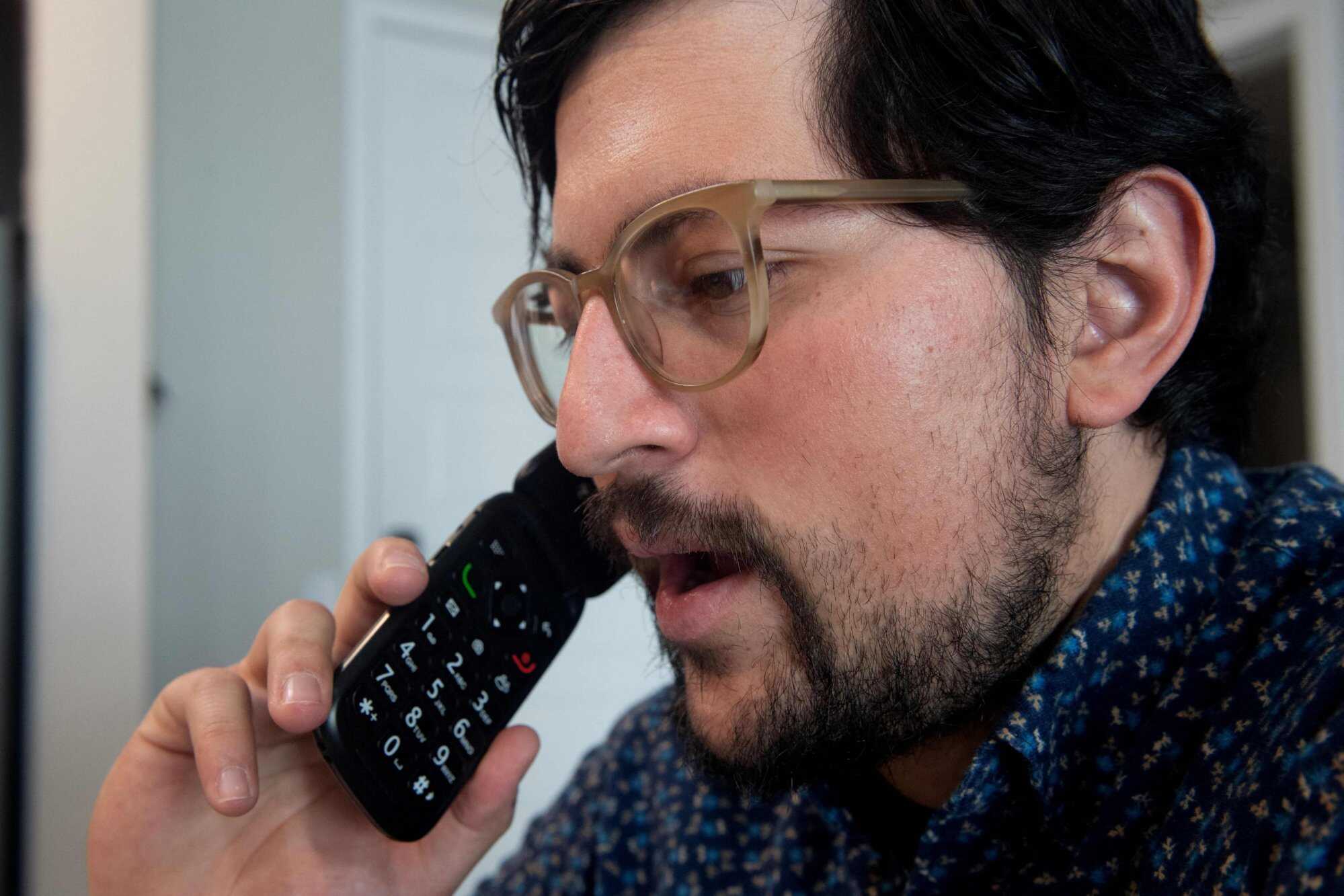 Briones speaks to a colleague while using his “dumbphone”. Photo: AFP