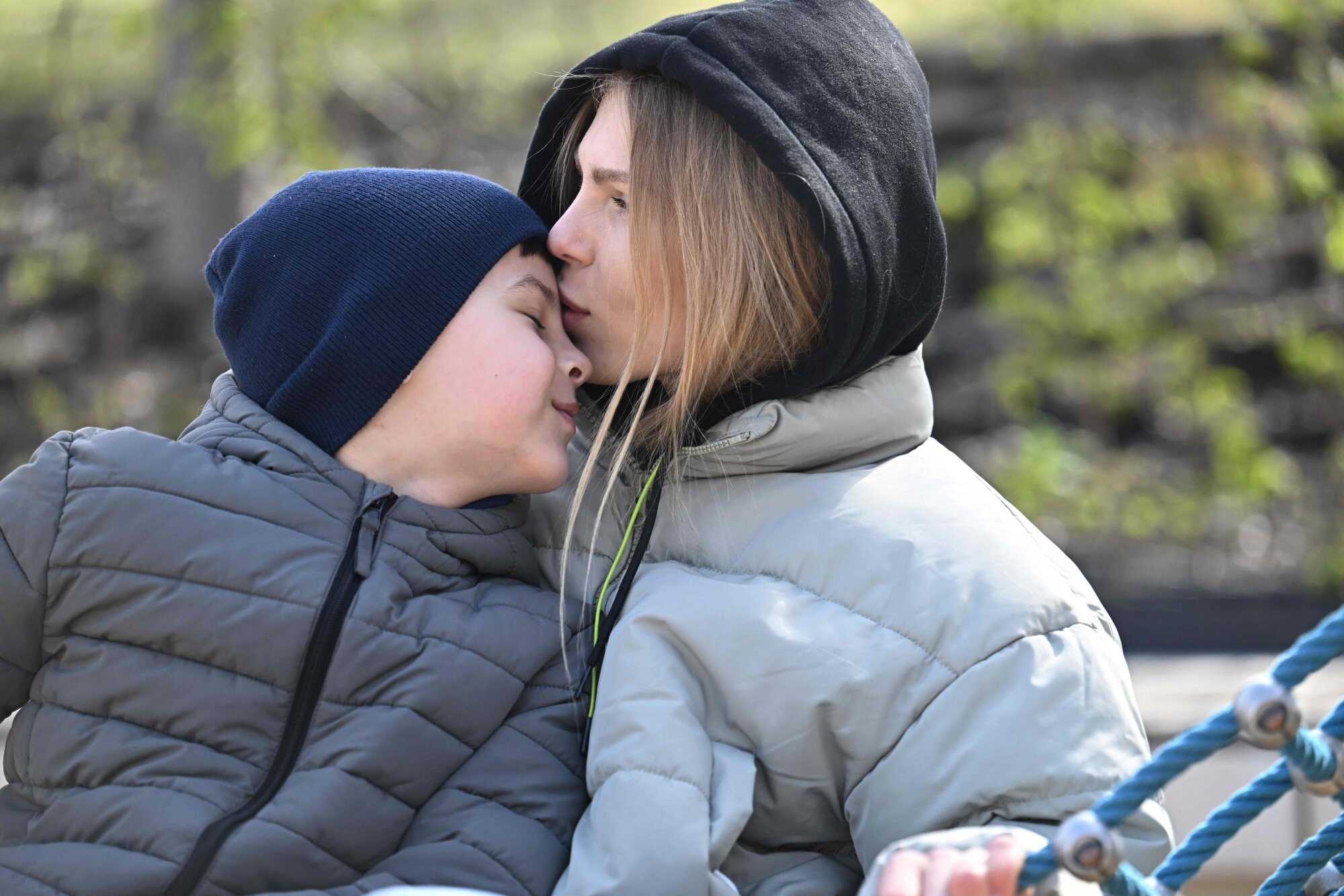 Iryna Bryk (R) kisses her son Roman (L). She said she fled war-torn Ukraine to protect her child. Photo: AFP