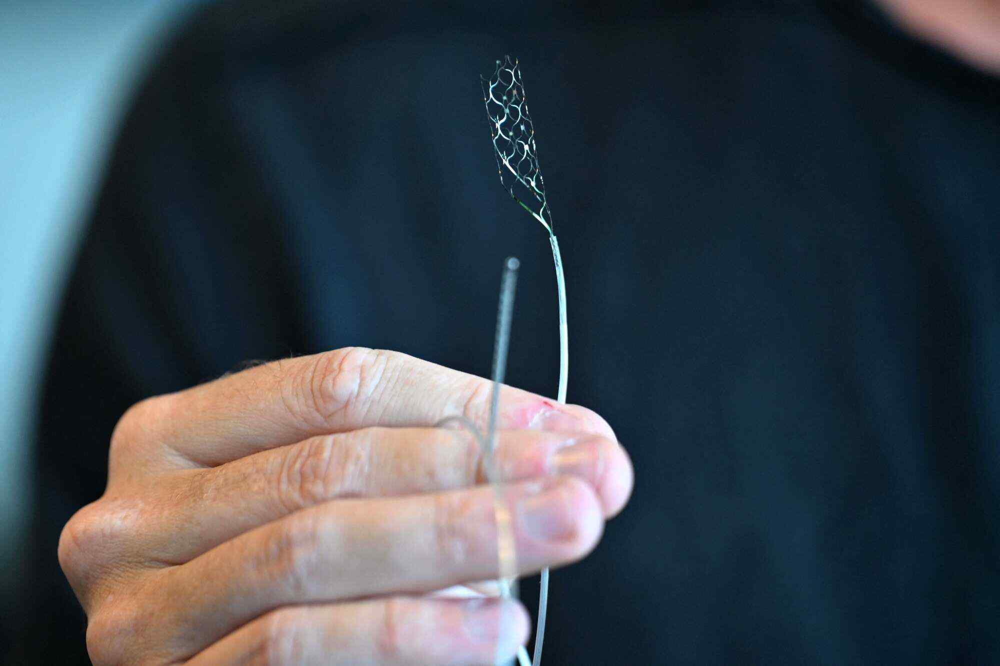 CEO and Founder of Synchron, Thomas Oxley, holds a stentrode implant. The implant allows the use of messaging apps and browsing online using only eye movements and thoughts. Photo: AFP