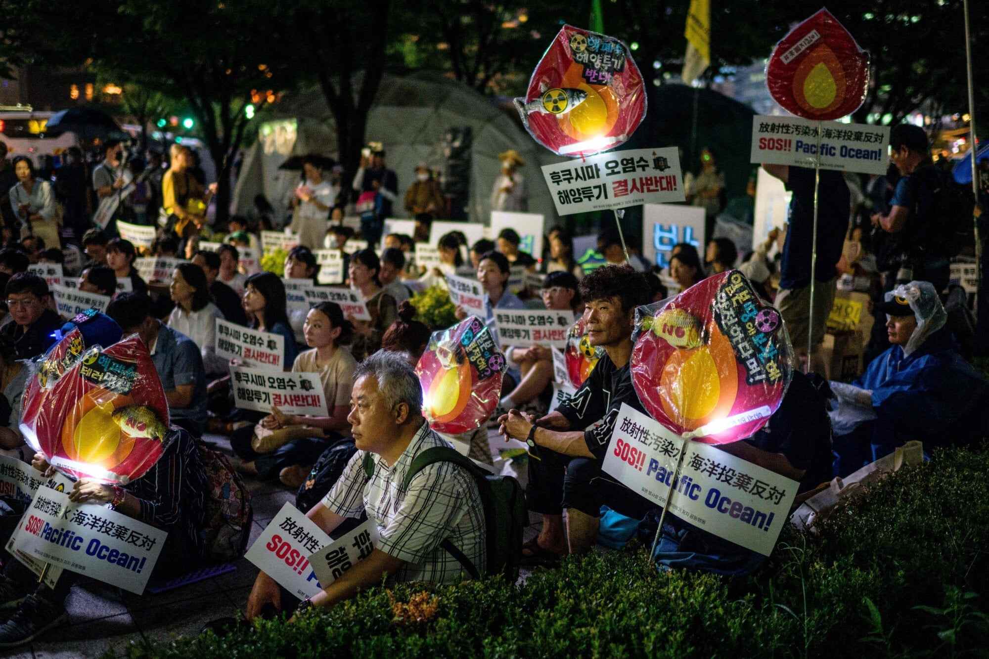 Activists in Seoul, South Korea hold placards reading “SOS!! Pacific Ocean!” as they protest against the planned release of wastewater from Japan’s stricken Fukushima nuclear plant on August 22, 2023. Photo: AFP