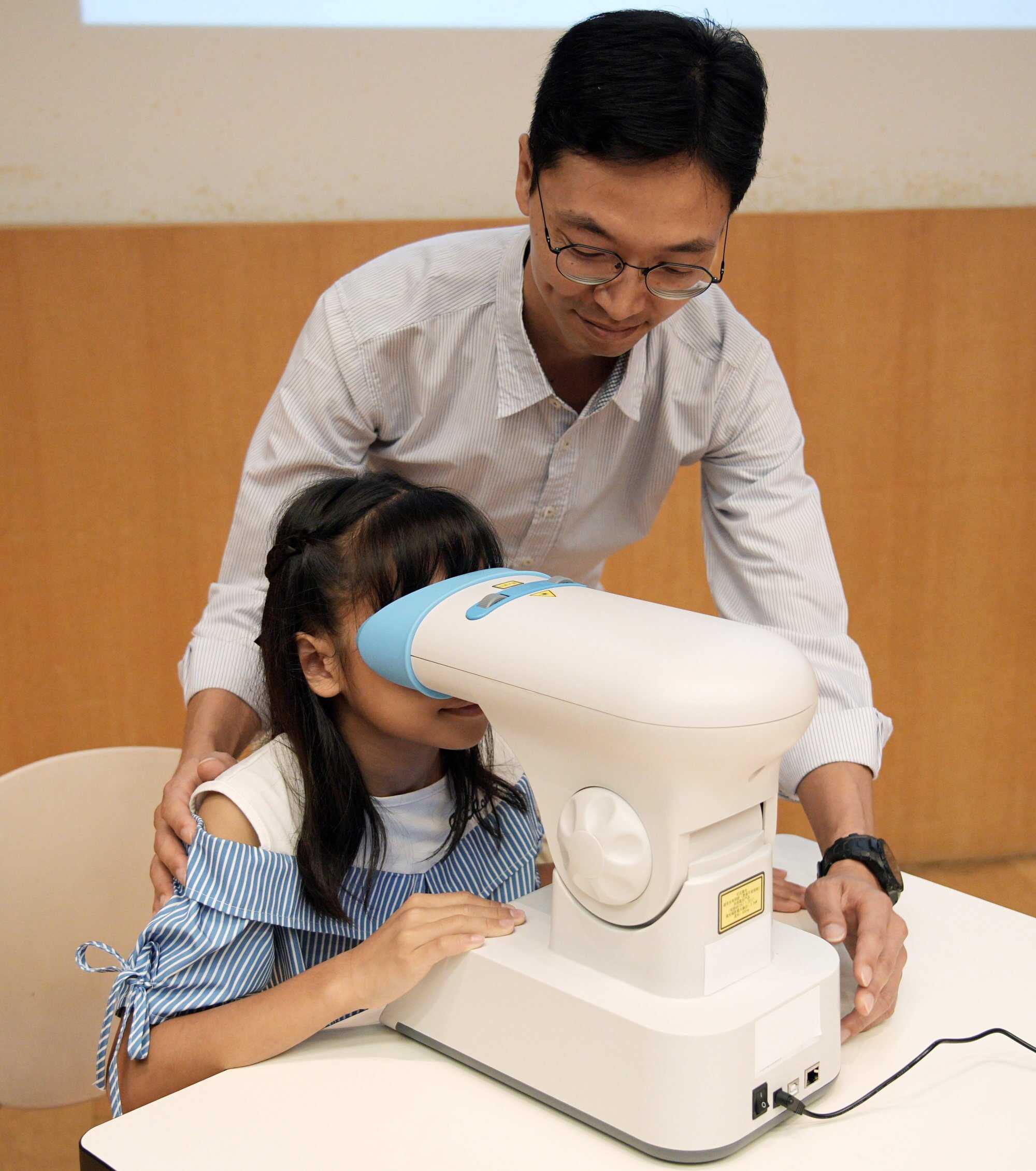 Kate Law (left) and her father Law Chi-kuen demonstrate a red light therapy device to help control Kate’s myopia. Photo: Harvey Kong
