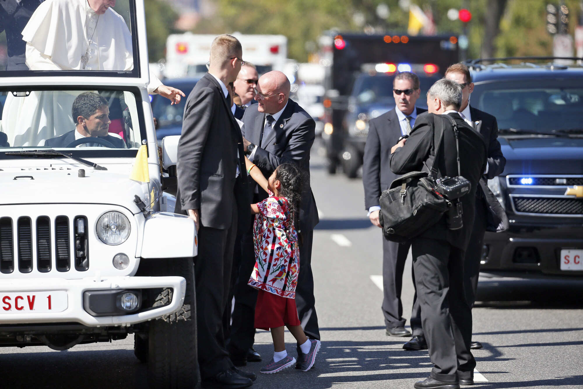 Pope Francis reaches for a letter and T-shirt from Sophie Cruz, during a parade in Washington. Photo: AP