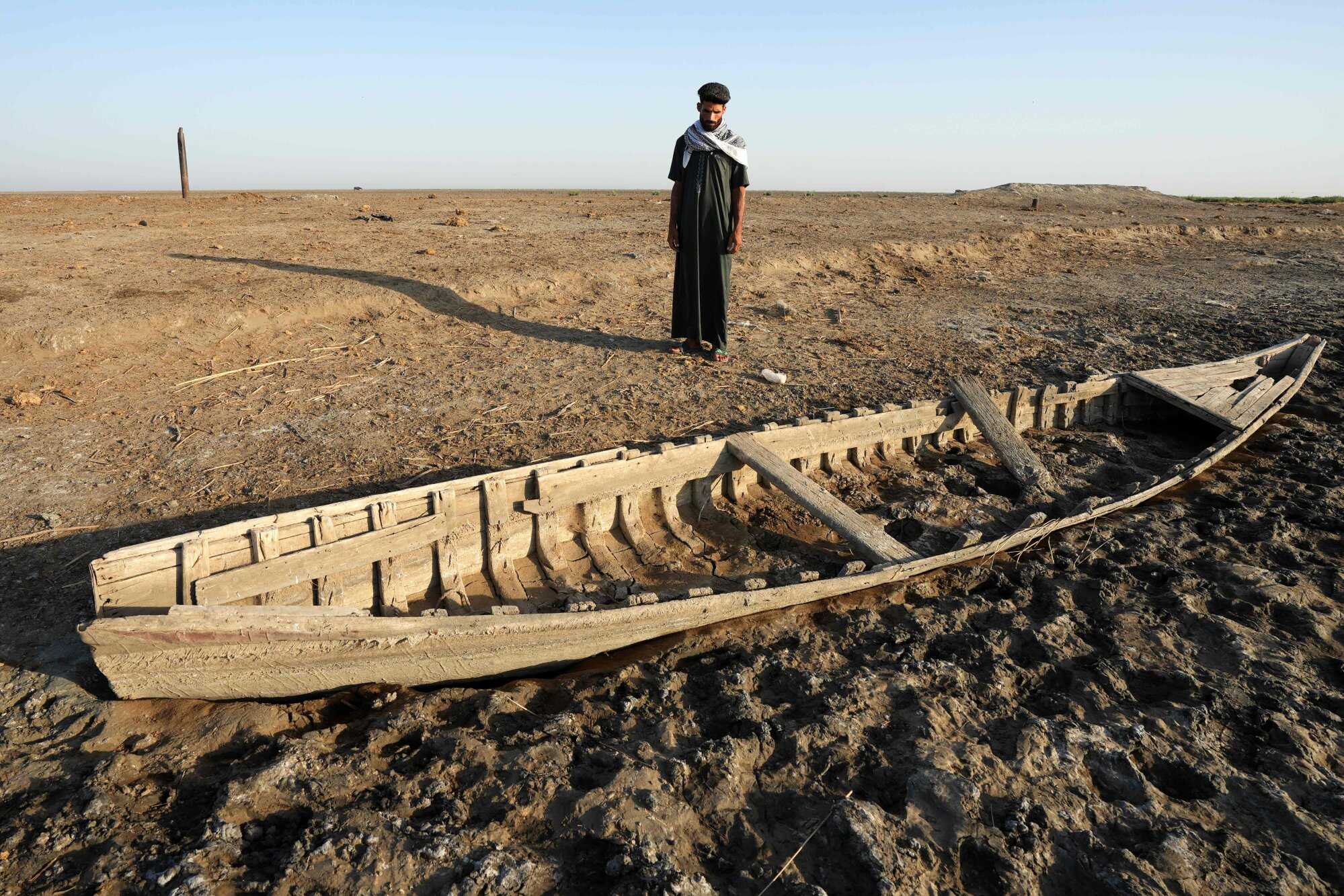 An Iraqi man looks at a grounded boat along a dried-up bank in the Chibayish marshes. Photo: AFP