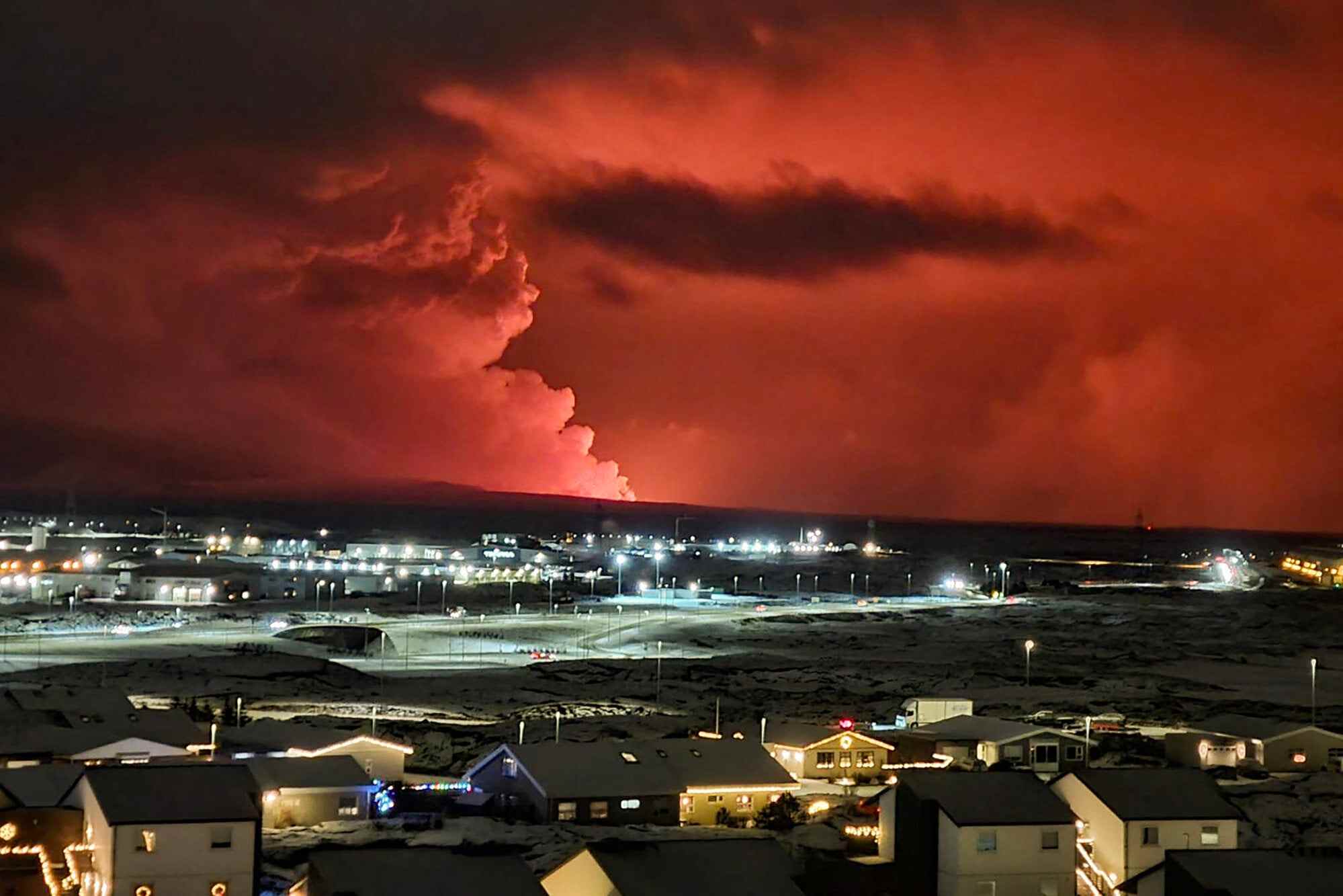 Houses in the village of Hafnarfjordur are seen as lava colours the night sky orange. Photo: TNS