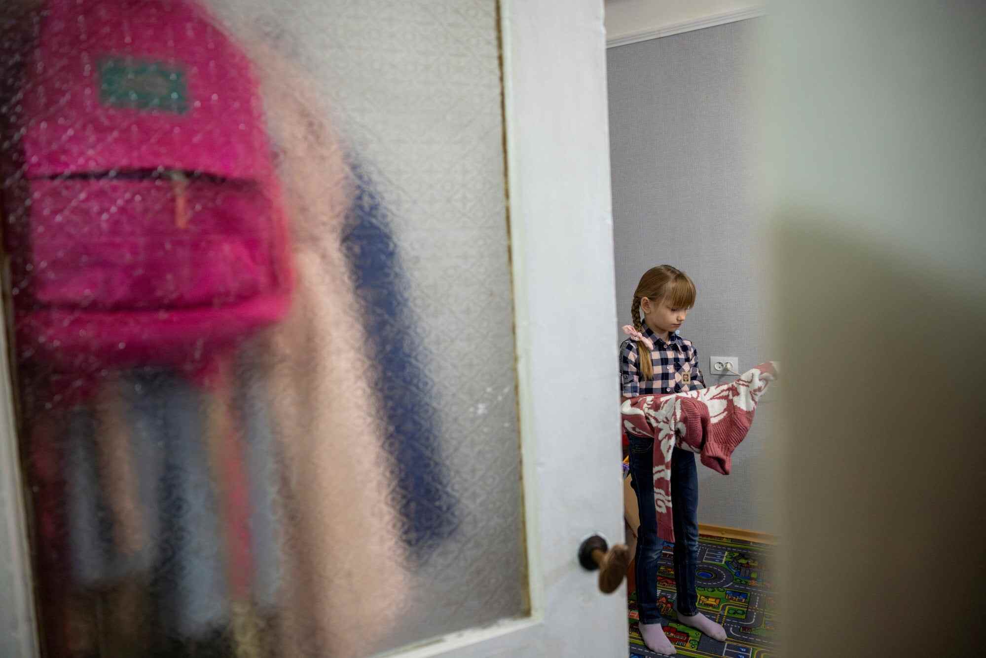 The unused school backpack of Ukrainian third-grader Arina Herasymova hangs behind the door of her bedroom as she gets ready for a walk after an online reading class in Sloviansk. Photo: Reuters