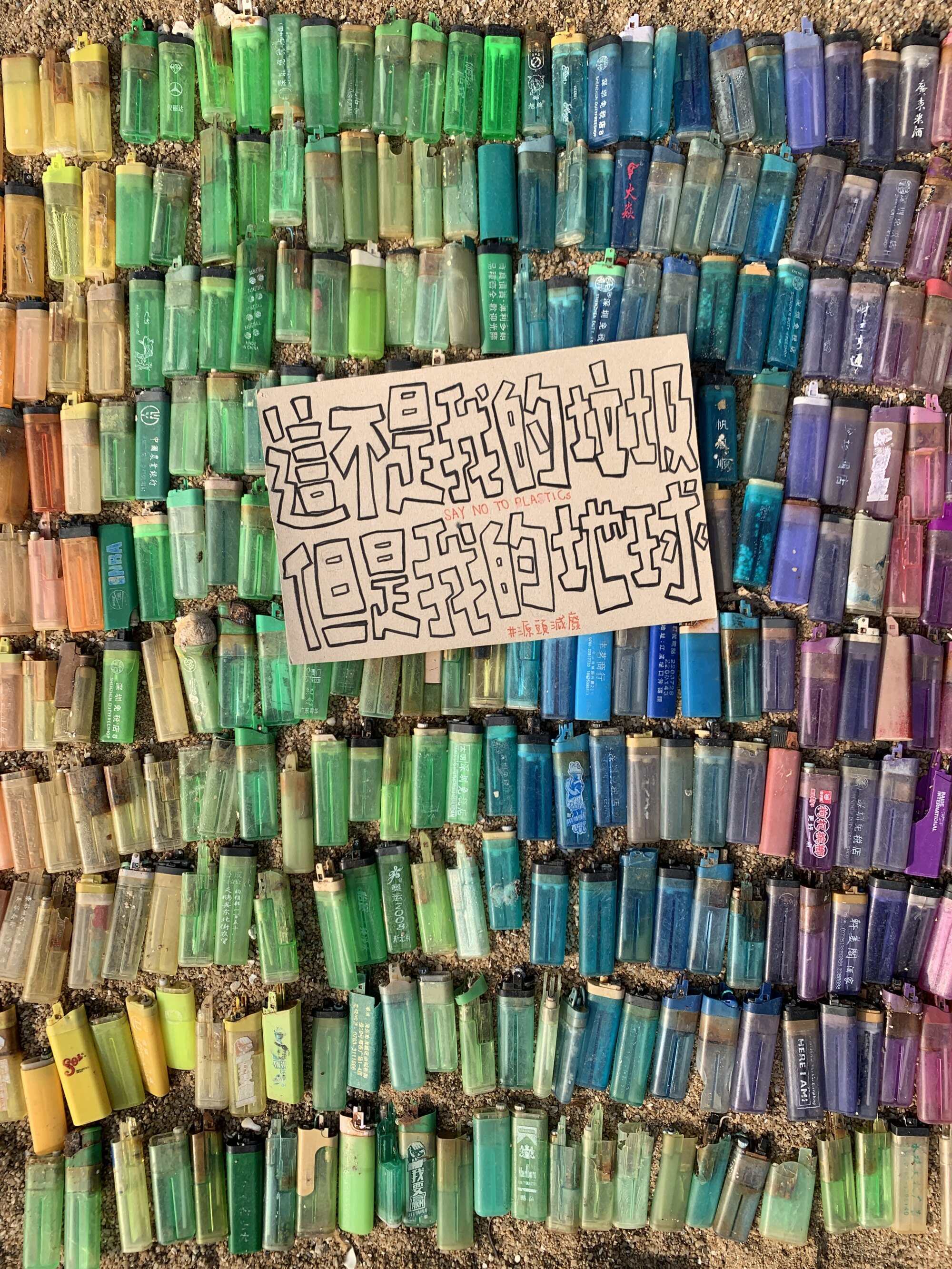 CraSea Cleanupper uses lighters containing plastic found in Tai O to create a backdrop for a sign that translates to: “This is not my rubbish, but this is my Earth”. Photo: Handout