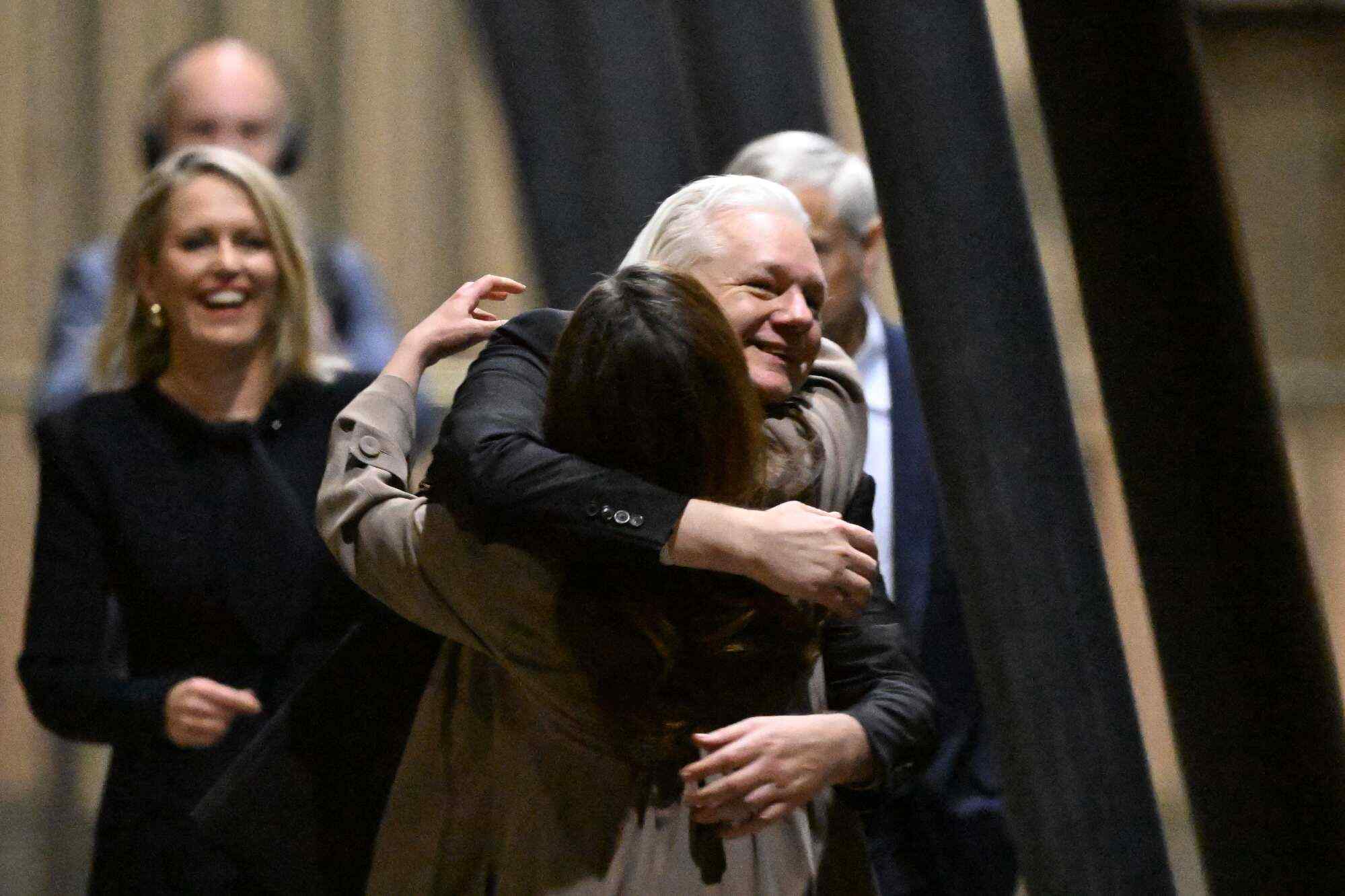 WikiLeaks founder Julian Assange (centre) hugs his wife Stella Assange (centre left) as he returns home to Australia after admitting he revealed US defence secrets in a deal that unlocked the door to his London prison cell. Photo: AFP