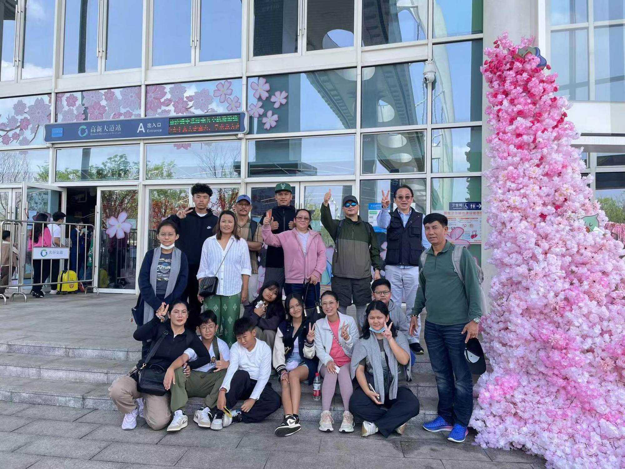The group takes a picture outside the main gate of the Wuhan Guanggu Suspended Monorail. Photo: Handout