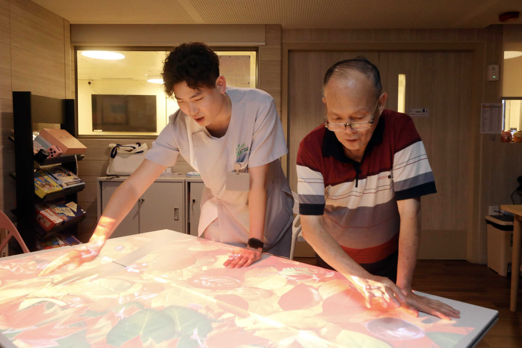 Kaden Yau plays an interactive game with an elderly resident of the care home. Photo: Sun Yeung