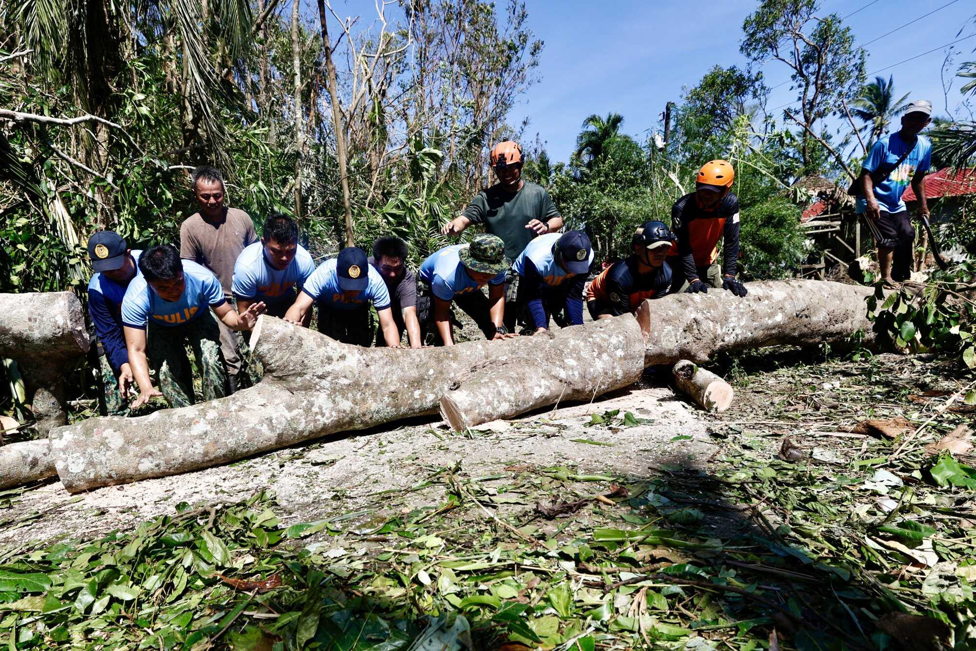 Police officers and villagers work to clear fallen trees and debris along a road in the typhoon-hit municipality of Claveria, Cagayan province, Philippines. Photo: EPA-EFE