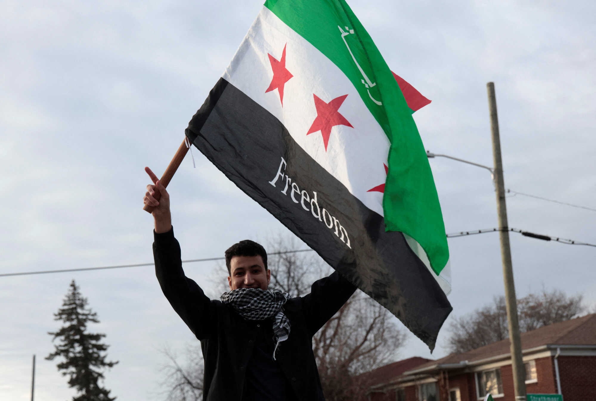 A person holds a Syrian opposition flag with the word “Freedom” as Syrian-Americans and supporters celebrate in Michigan, United States. Photos: Reuters