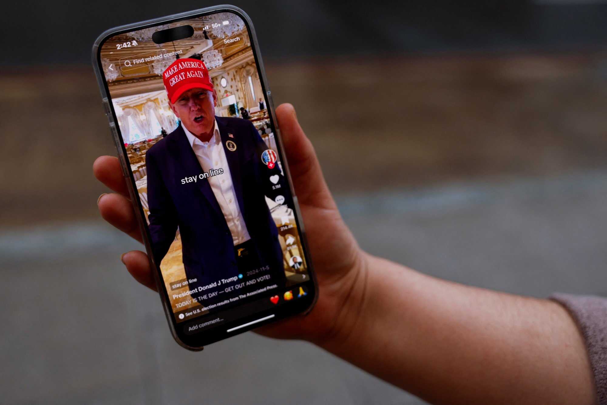 A woman poses with her smartphone displaying the @realdonaldtrump TikTok page on January 19. Photo: Reuters