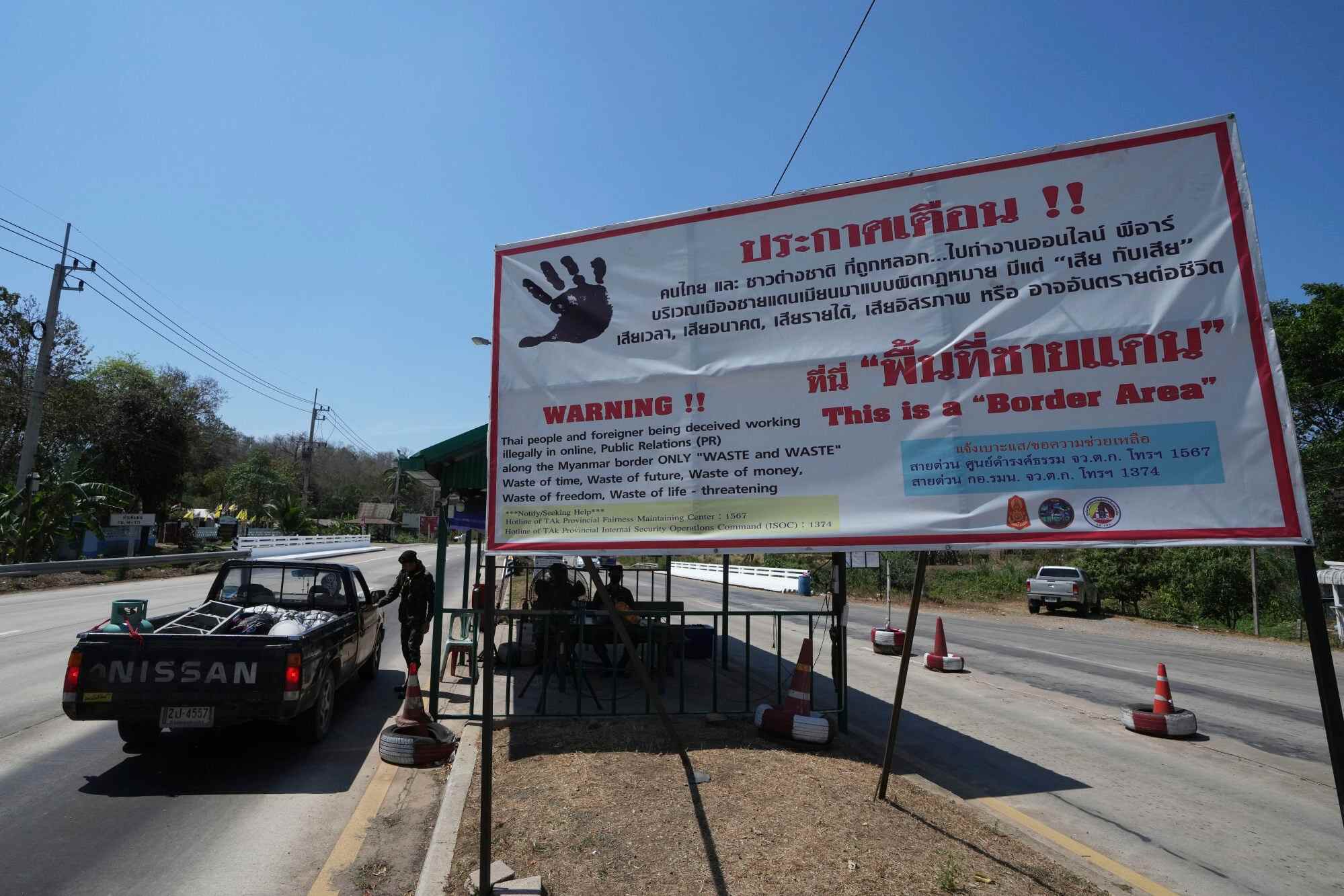 A truck pass through a military checkpoint near display signs warning people of the risk of being trafficked to work along the Myanmar border in Mae Sot, Thailand. Photo: AP