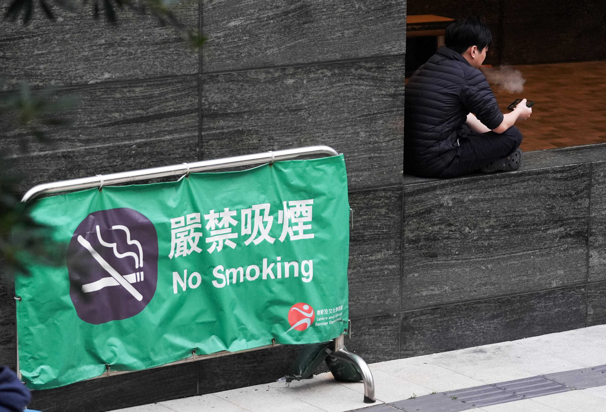Cigarette smokers outside a mall, near a “No Smoking banner, in Kowloon Tong. Photo: Eugene Lee