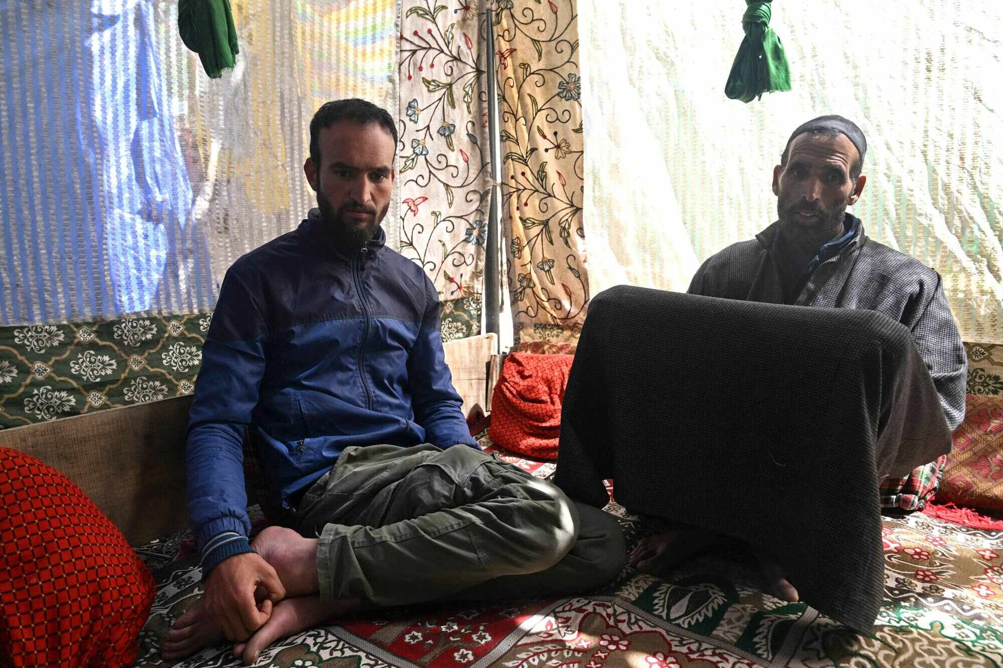 Syed Haidar Shah (right) and Naushad Hussain, the father and brother of slain Kashmiri horseman Syed Adil Shah, sit inside their village home. Photo: AFP