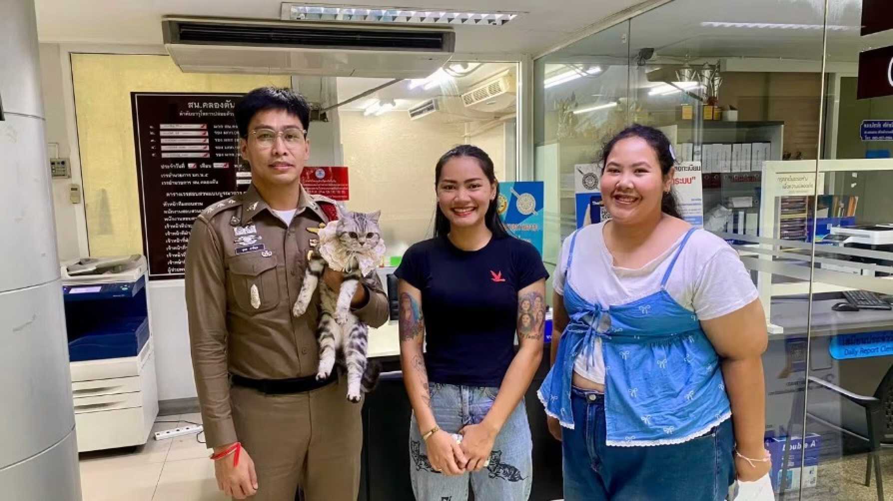 The cat’s owners posed for a farewell photo with the kind-hearted police officer who released the feline without any charges. Photo: Parinda Yukol Pakeesuk/Facebook