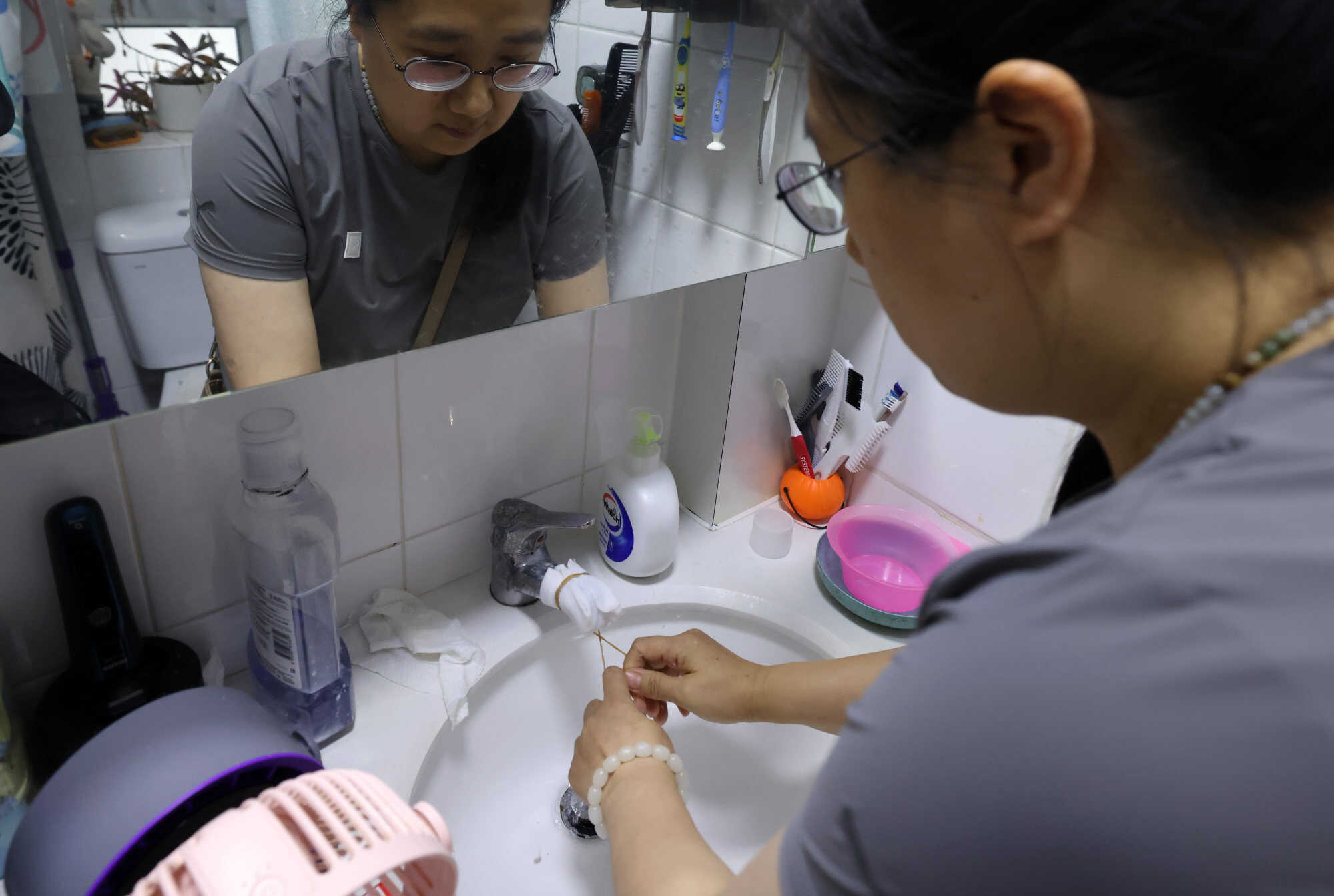 A resident wraps a tap with tissue to filter out black particles. Photo: Nora Tam