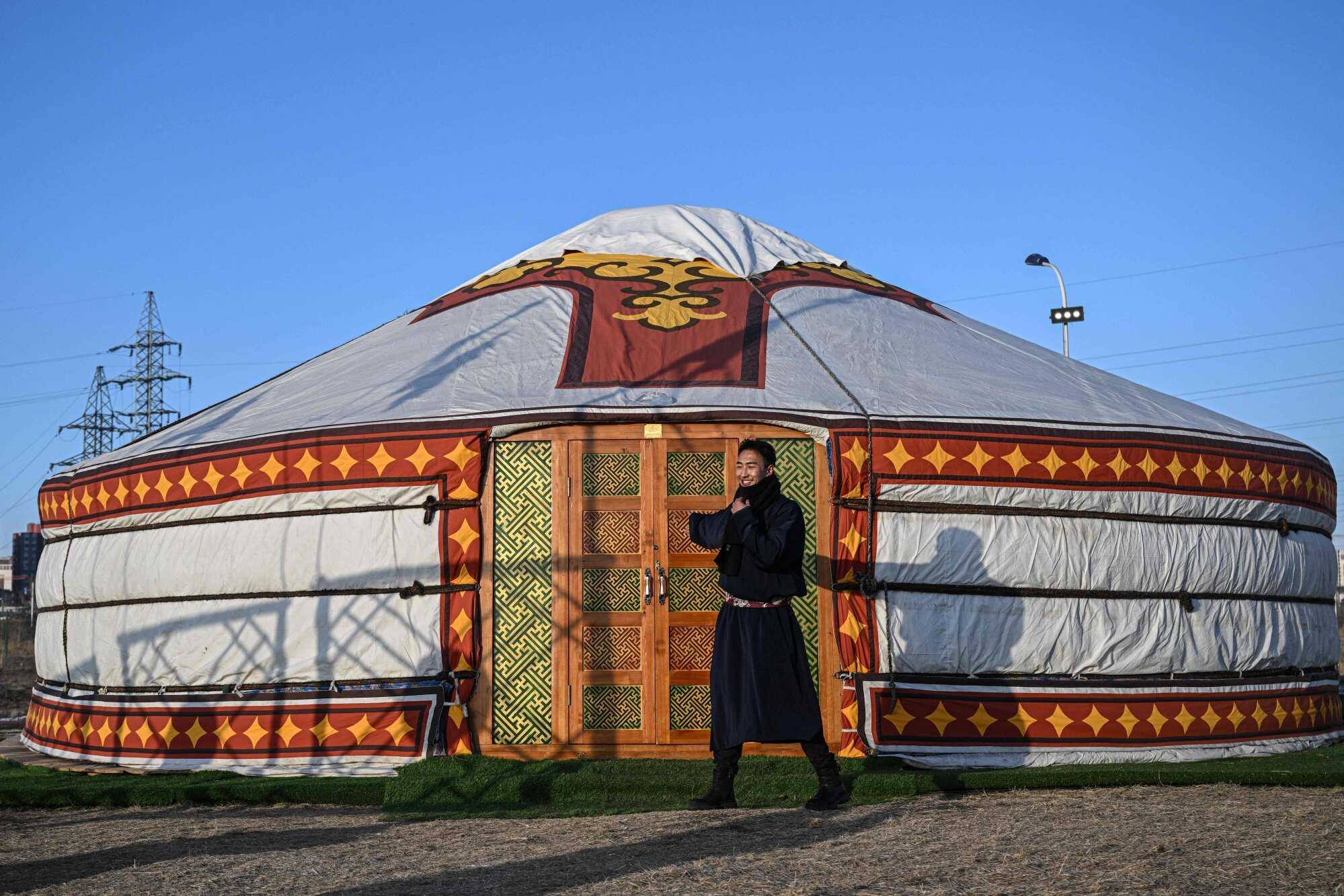 A man in a traditional Mongolian costume stands outside a Mongolian tent. Photo: AFP