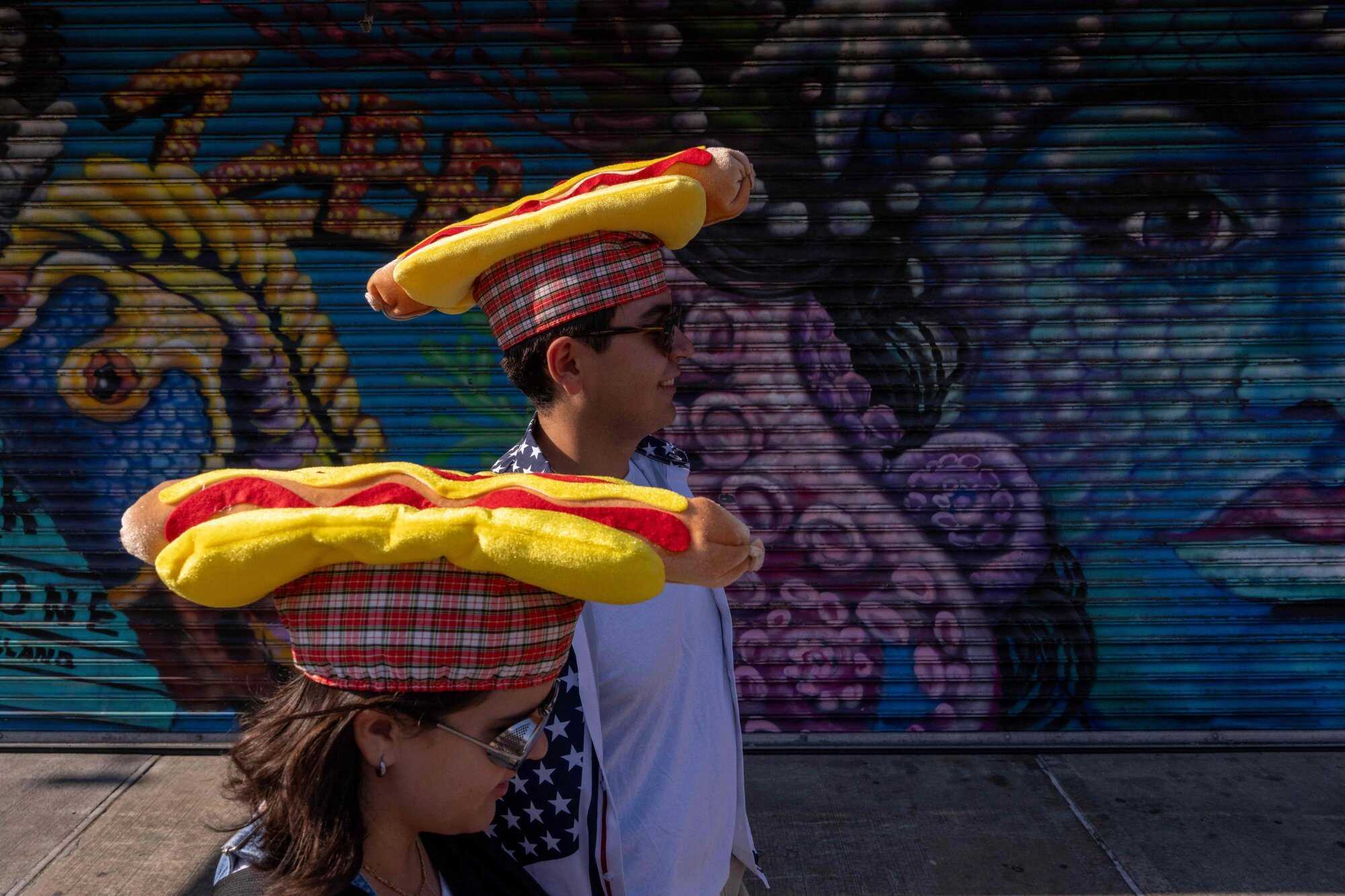 Two people wearing hotdog hats line up to watch Nathan’s Annual Hot Dog Eating Contest in New York City. Photo: Getty Images via AFP