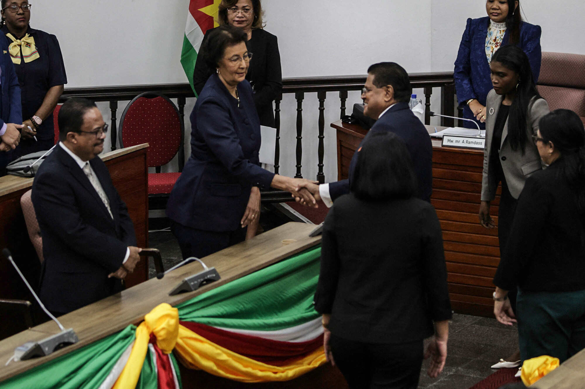Suriname’s leader Jennifer Geerlings-Simons shakes hands with the outgoing president, Chan Santokhi. Photo: AFP