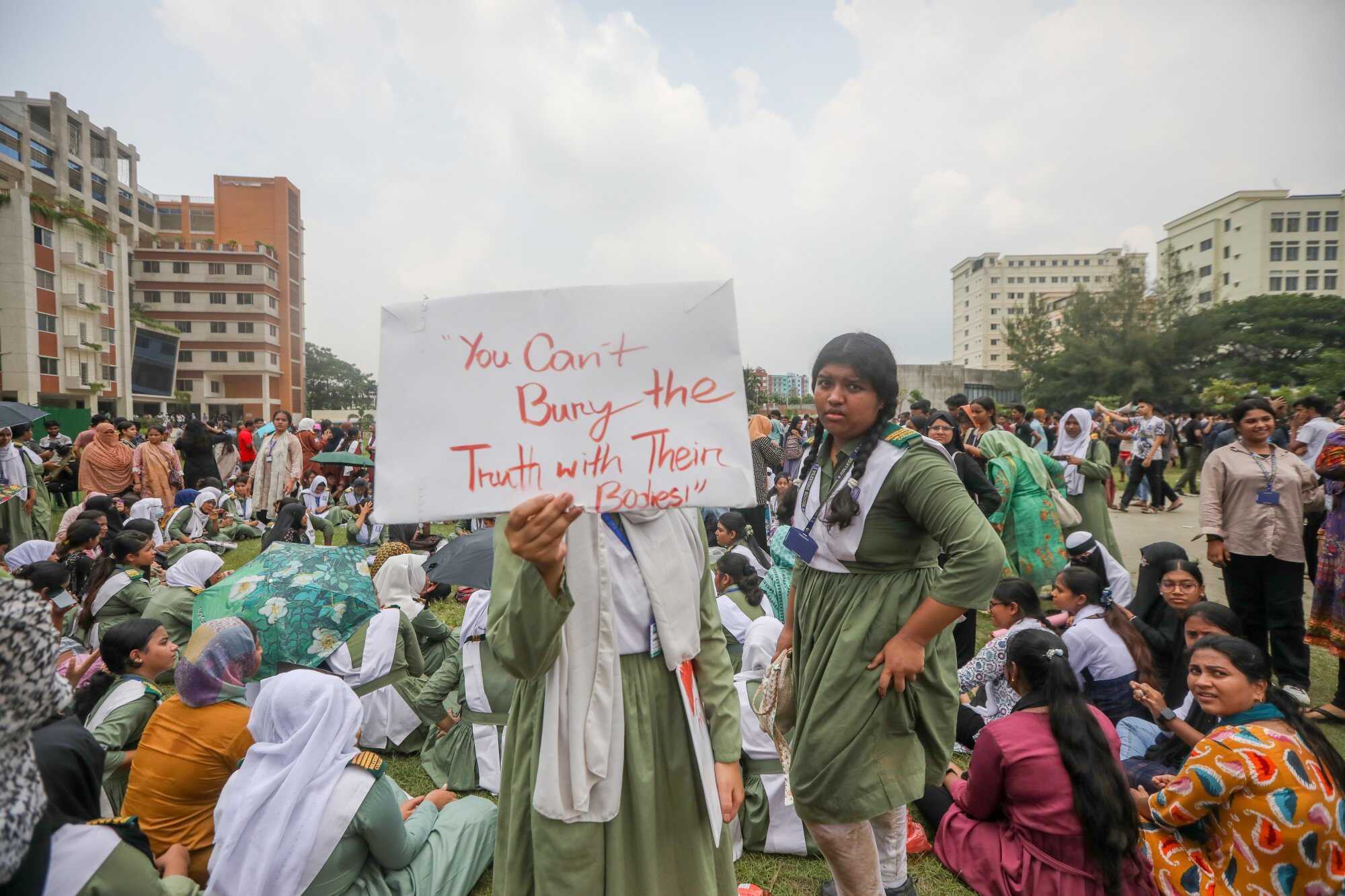 Bangladeshi students shout slogans and hold placards near the crash site. Photo: EPA